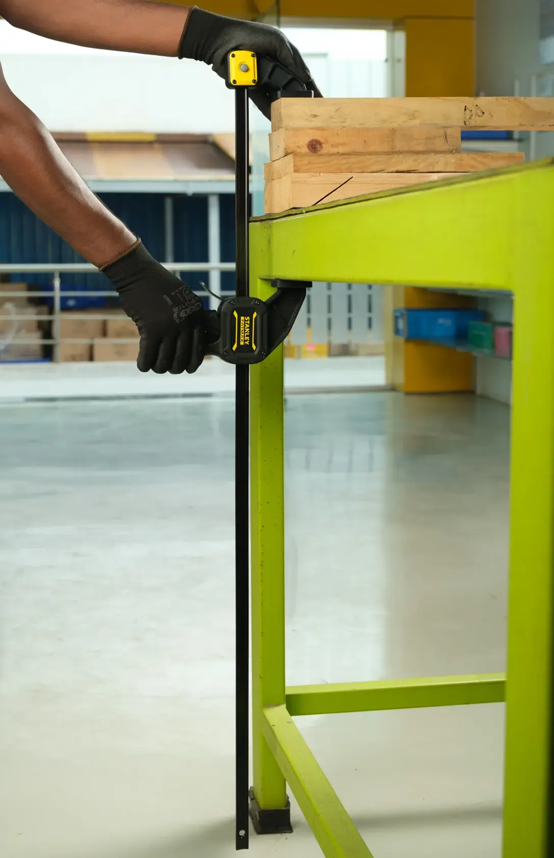 STANLEY FMHT0-83237 photography of bar clamp securing wooden boards to a bright green workbench.