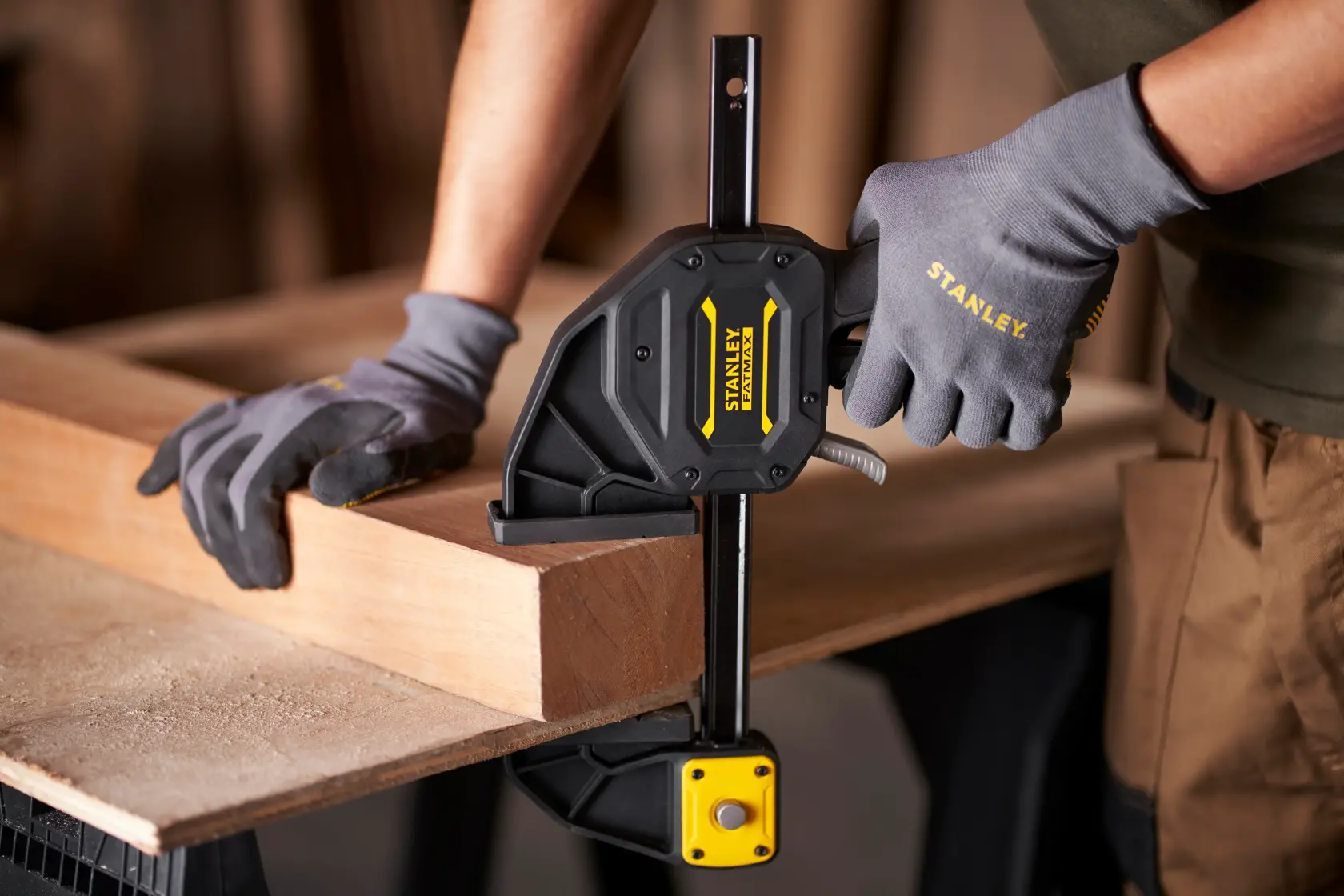 Stanley FMHT0-83238 photography of a one-handed clamp securing wood on a workbench.