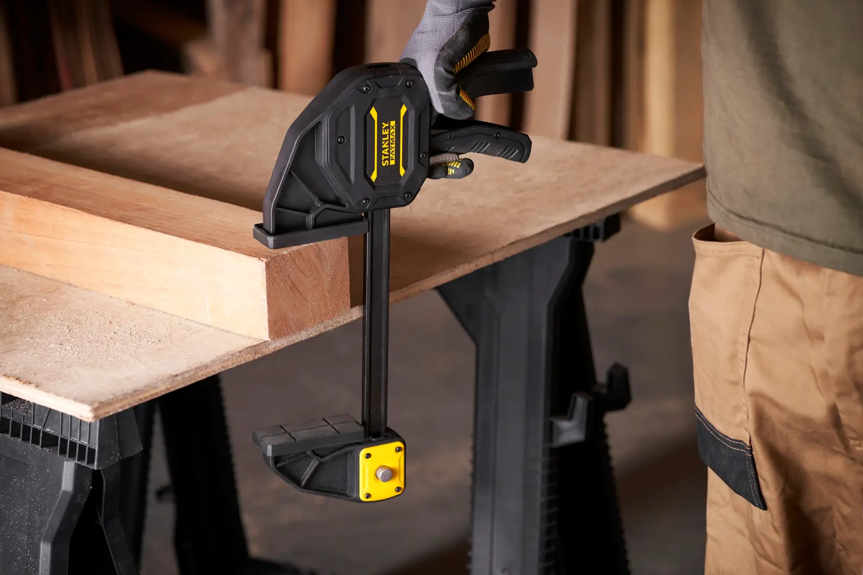 Stanley FMHT0-83238 trigger clamp securing wood on workbench, side angle view.