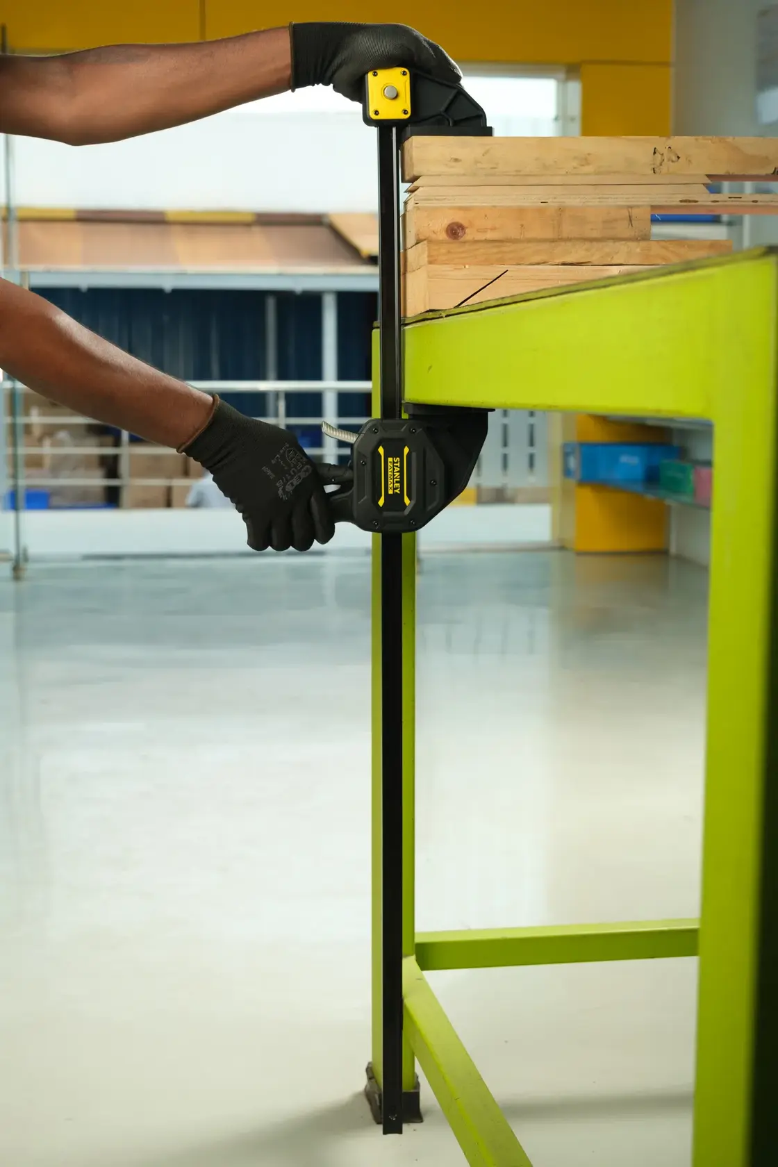 Stanley FMHT0-83241 bar clamp in use securing wood on a green workbench, close-up side angle.