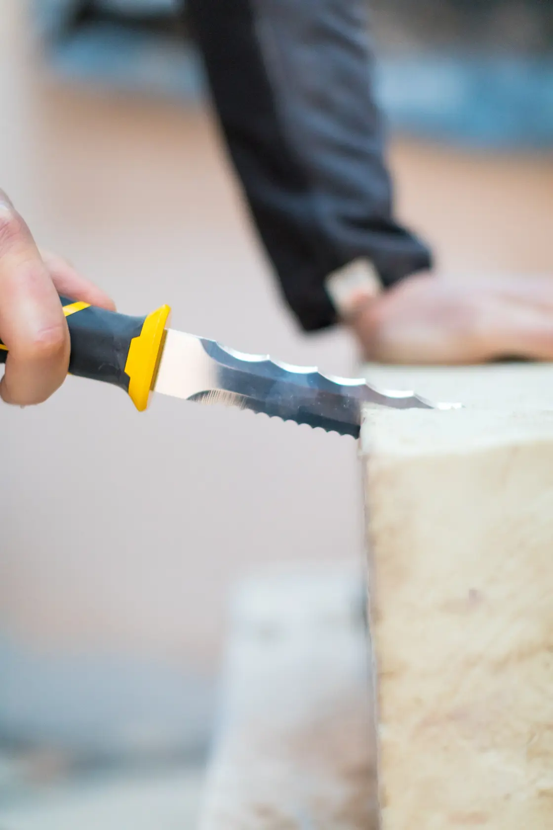 STANLEY FMHT10327-1 insulation knife with yellow and black handle cutting through insulation material, close up.