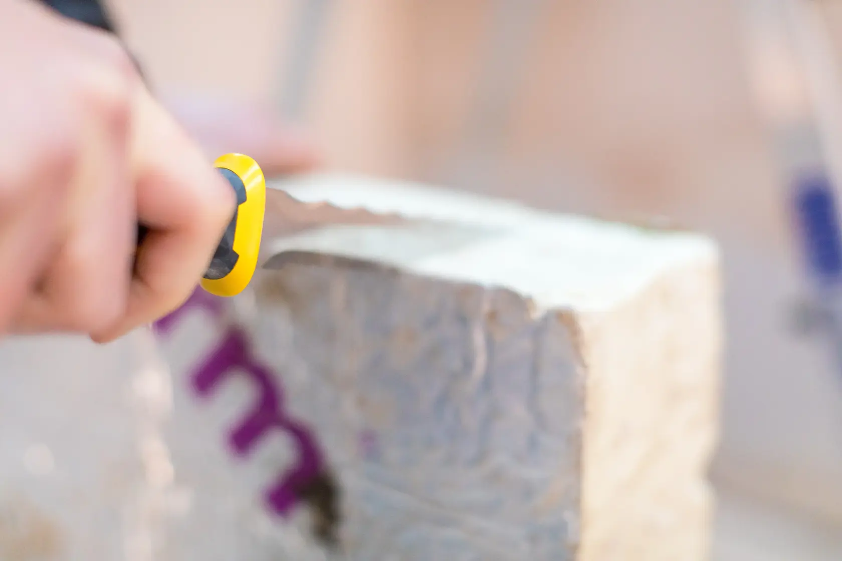 STANLEY FMHT10327-1 utility knife with yellow and black handle cutting insulation material, close-up.