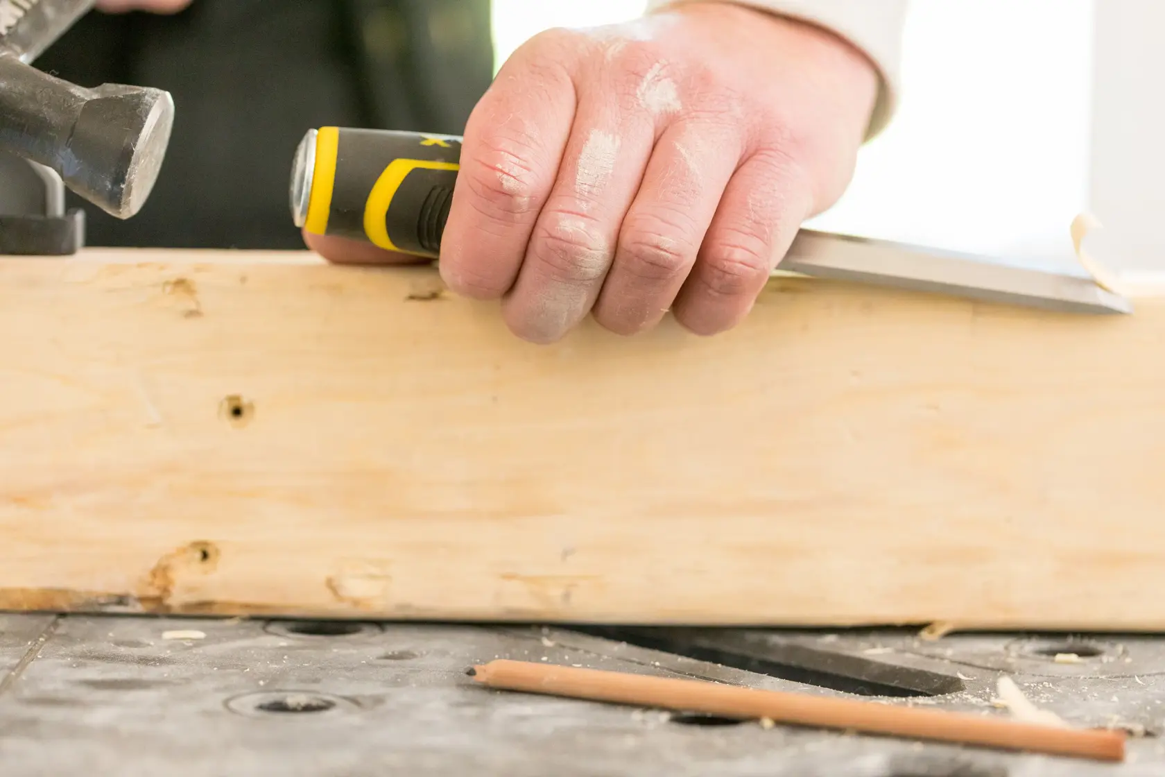 STANLEY FMHT16693-0 chisel with yellow and black handle in hand carving wood close-up.