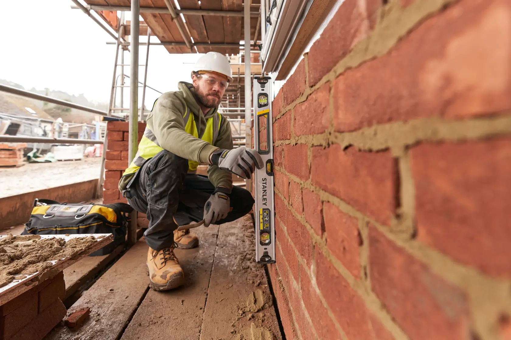 STANLEY FMHT43672 spirit level used by construction worker against brick wall at building site.