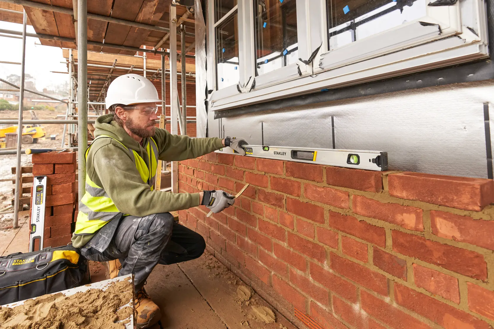 STANLEY FMHT43676-1 spirit level used by a builder measuring brick wall alignment on a construction site.