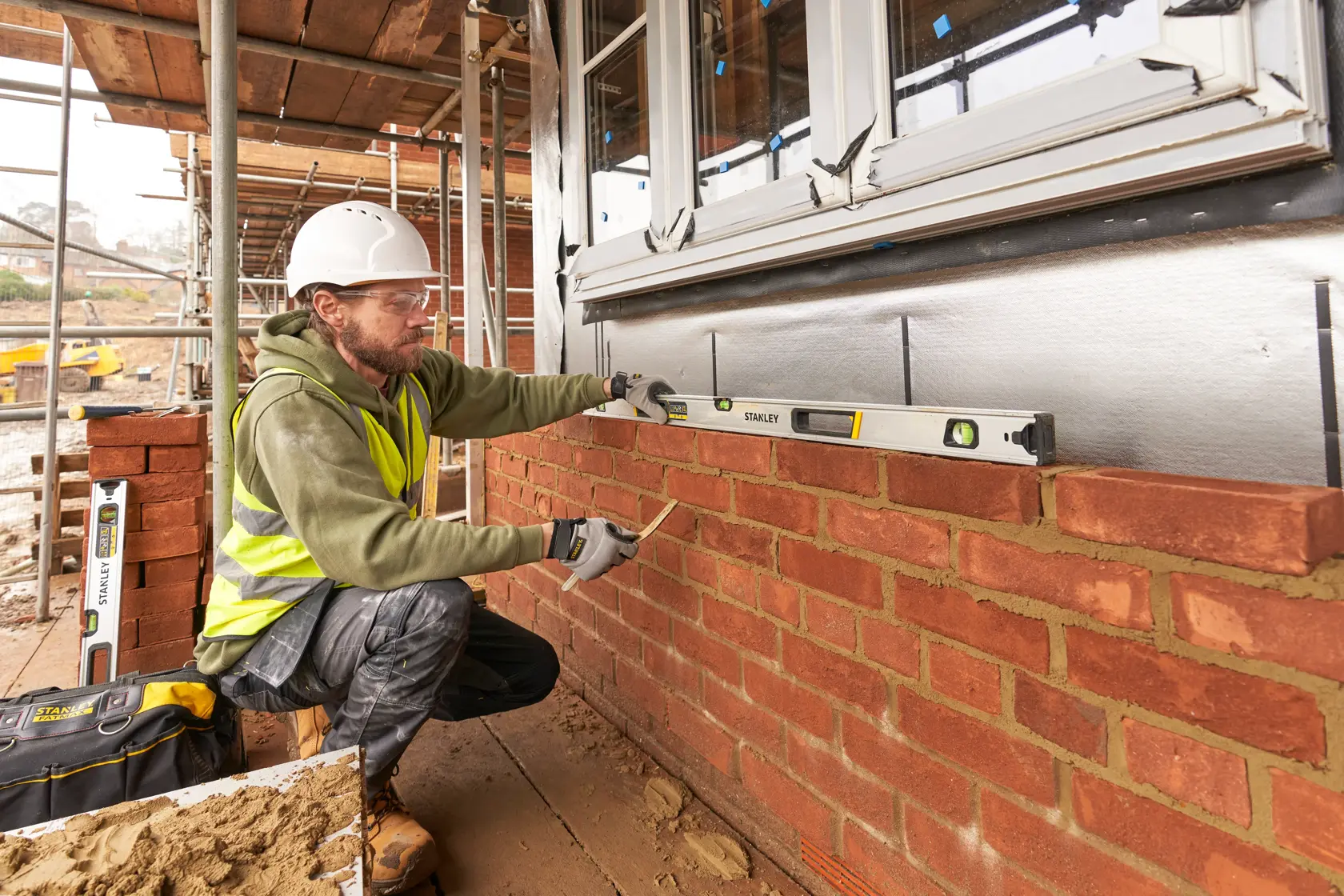 Photo of STANLEY FMHT43677 spirit level in use by a builder on a brick wall at a construction site.