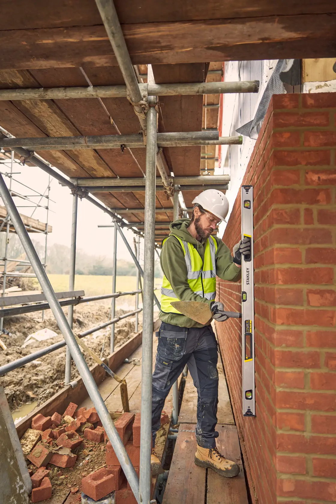STANLEY FMHT43677 spirit level used by construction worker to check brick wall alignment on building site.