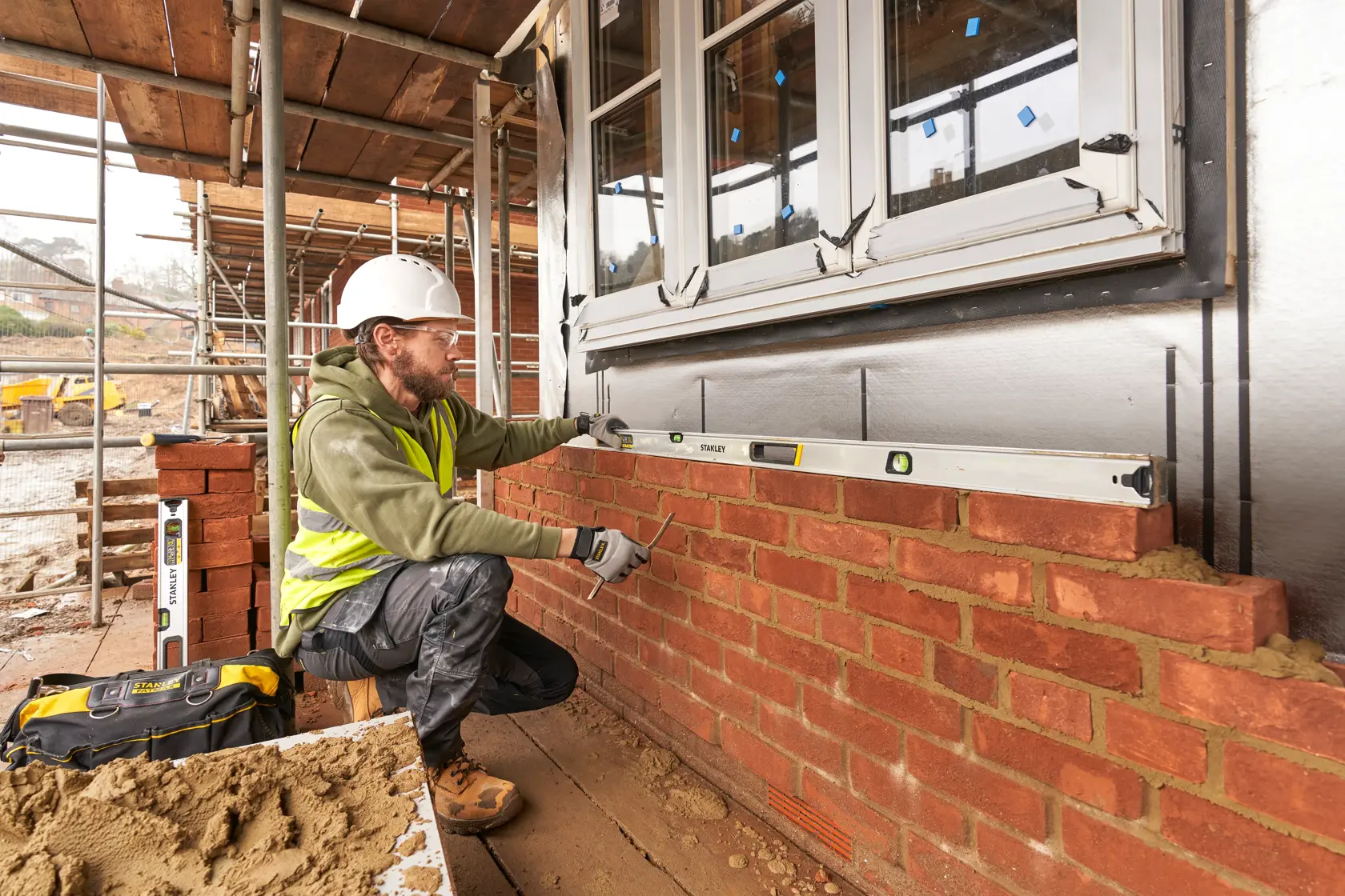 Photo of STANLEY FMHT43680-1 spirit level used by a worker aligning bricks on a construction site.