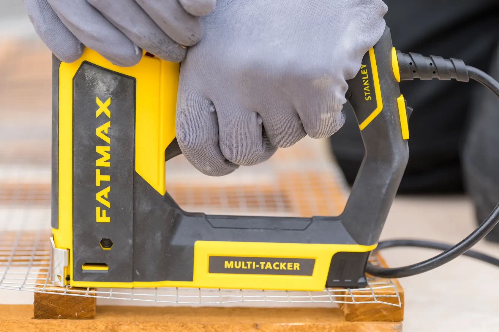 STANLEY FMHT6-75934 multi-tacker tool in use, yellow and black, close-up side angle.