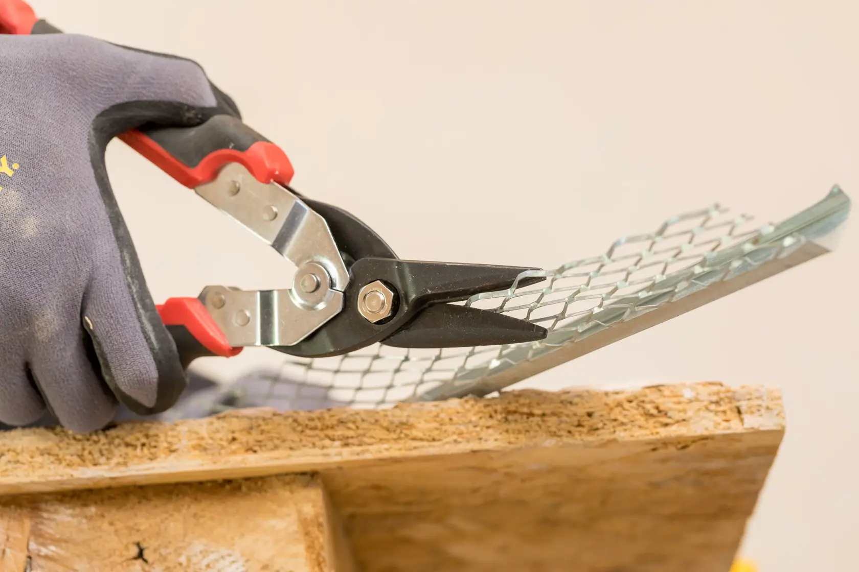 STANLEY FMHT73755 aviation snips cutting metal mesh, close-up photo with gloved hand.