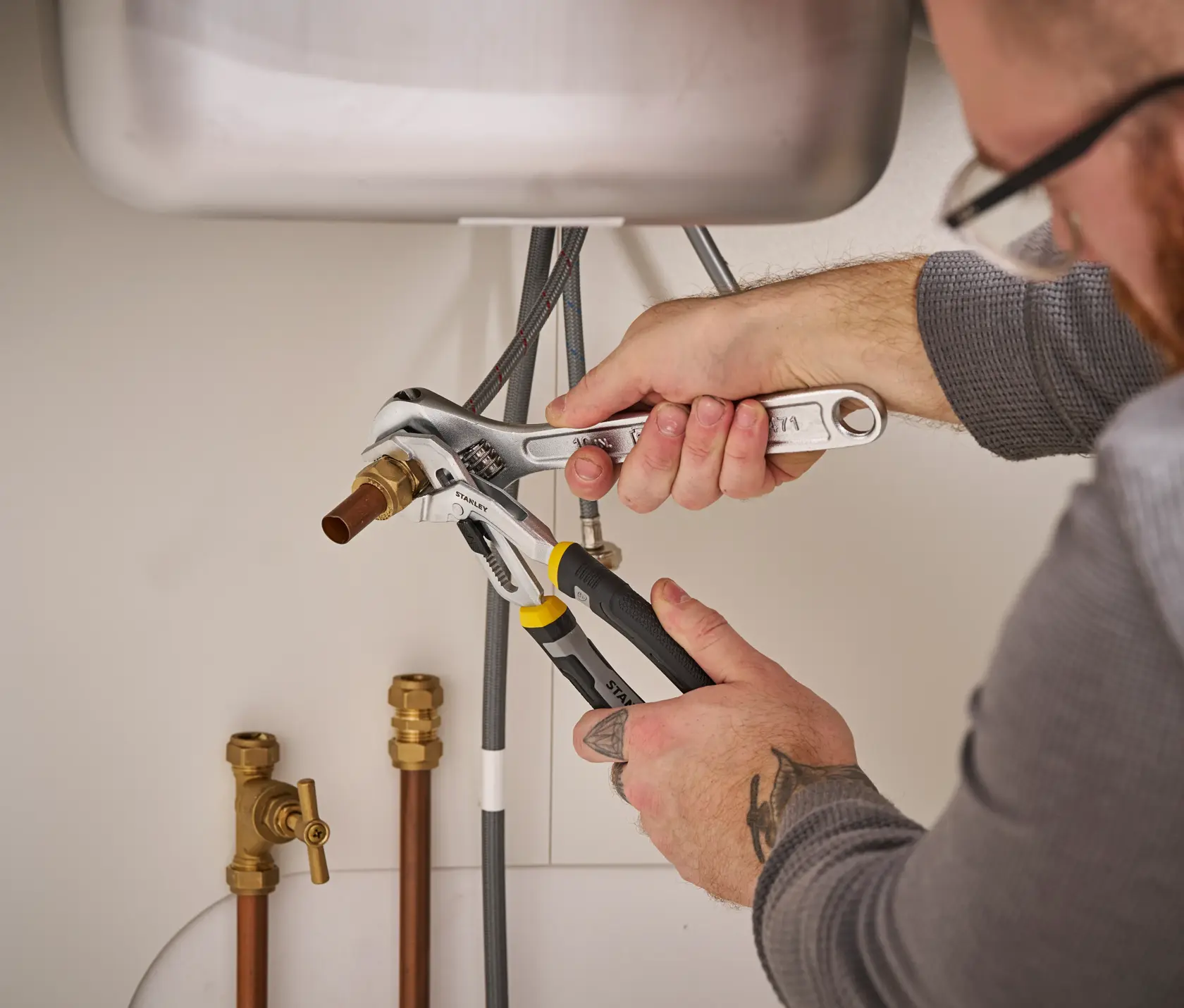 Photo of STANLEY FMHT75508-0 pliers being used to grip pipe under sink during plumbing work.