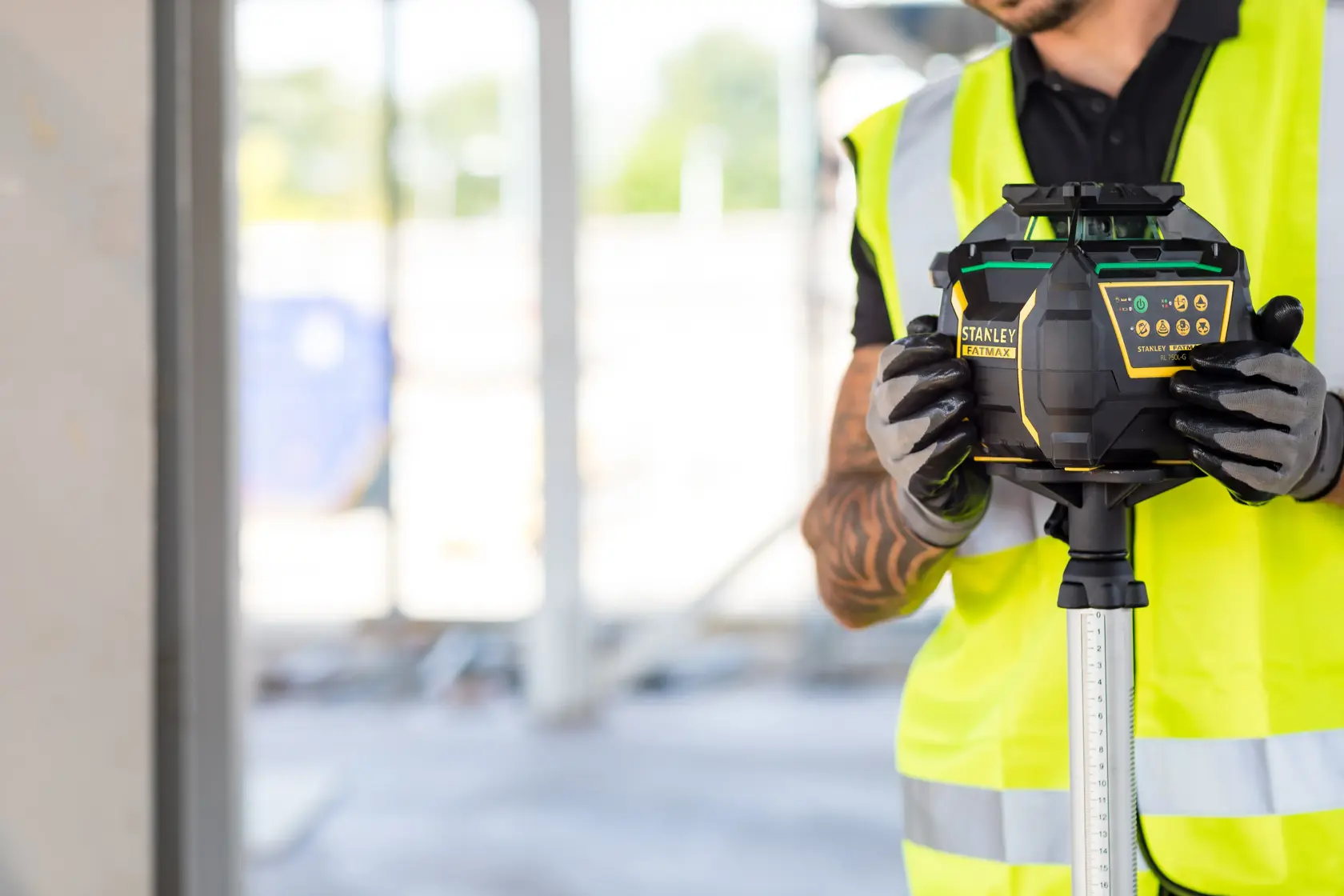 STANLEY FMHT77223-1 rotary laser level held by worker in hi-vis vest at construction site