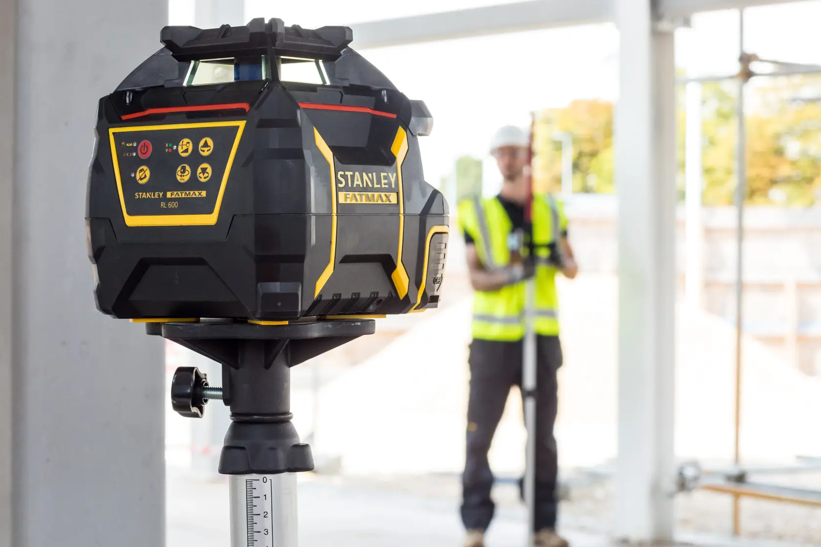 STANLEY FMHT77446-1 laser level in use at construction site, mounted on tripod, shown in close-up.