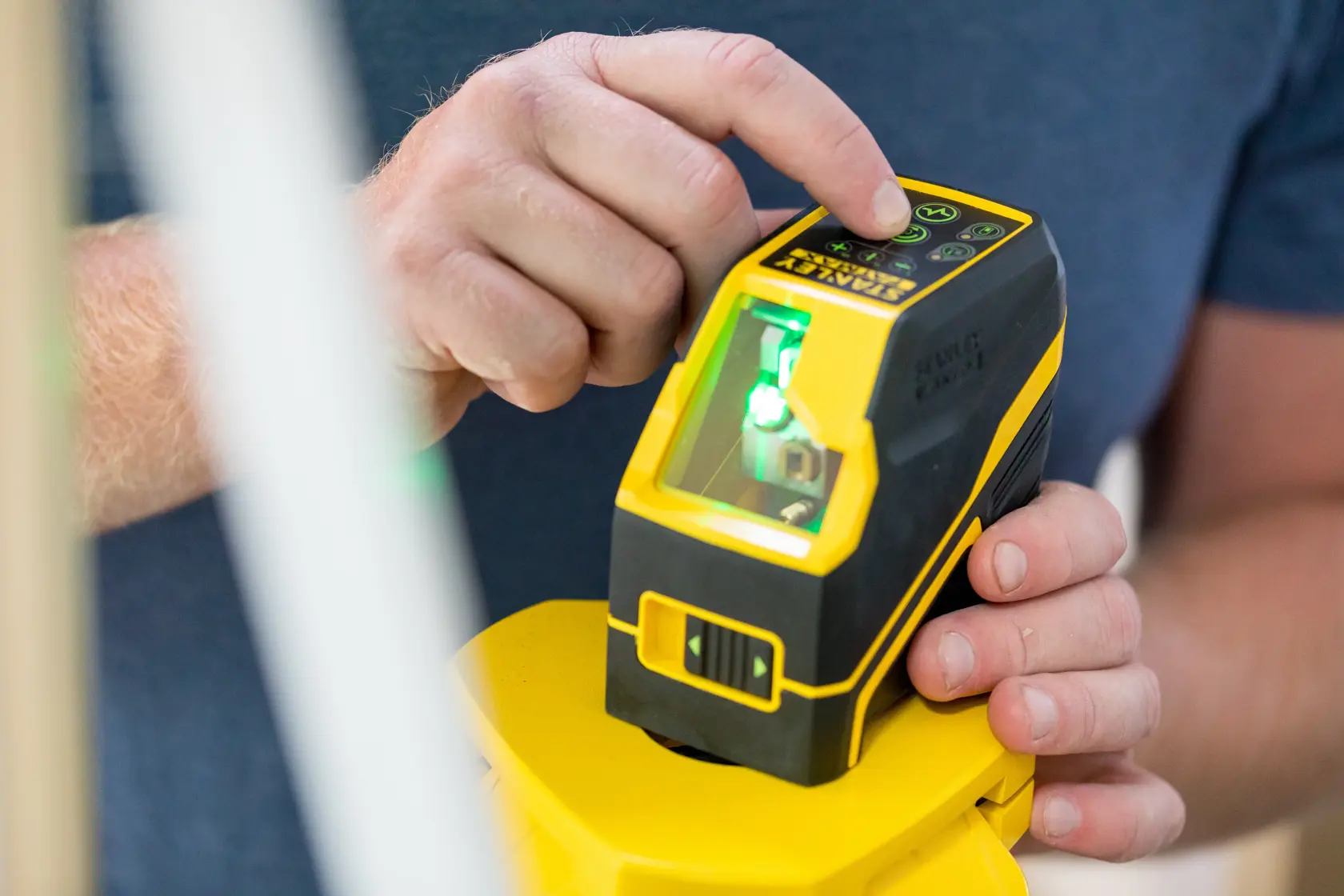Photo of STANLEY FMHT77586-1 laser level in use, yellow and black handheld tool with digital controls.