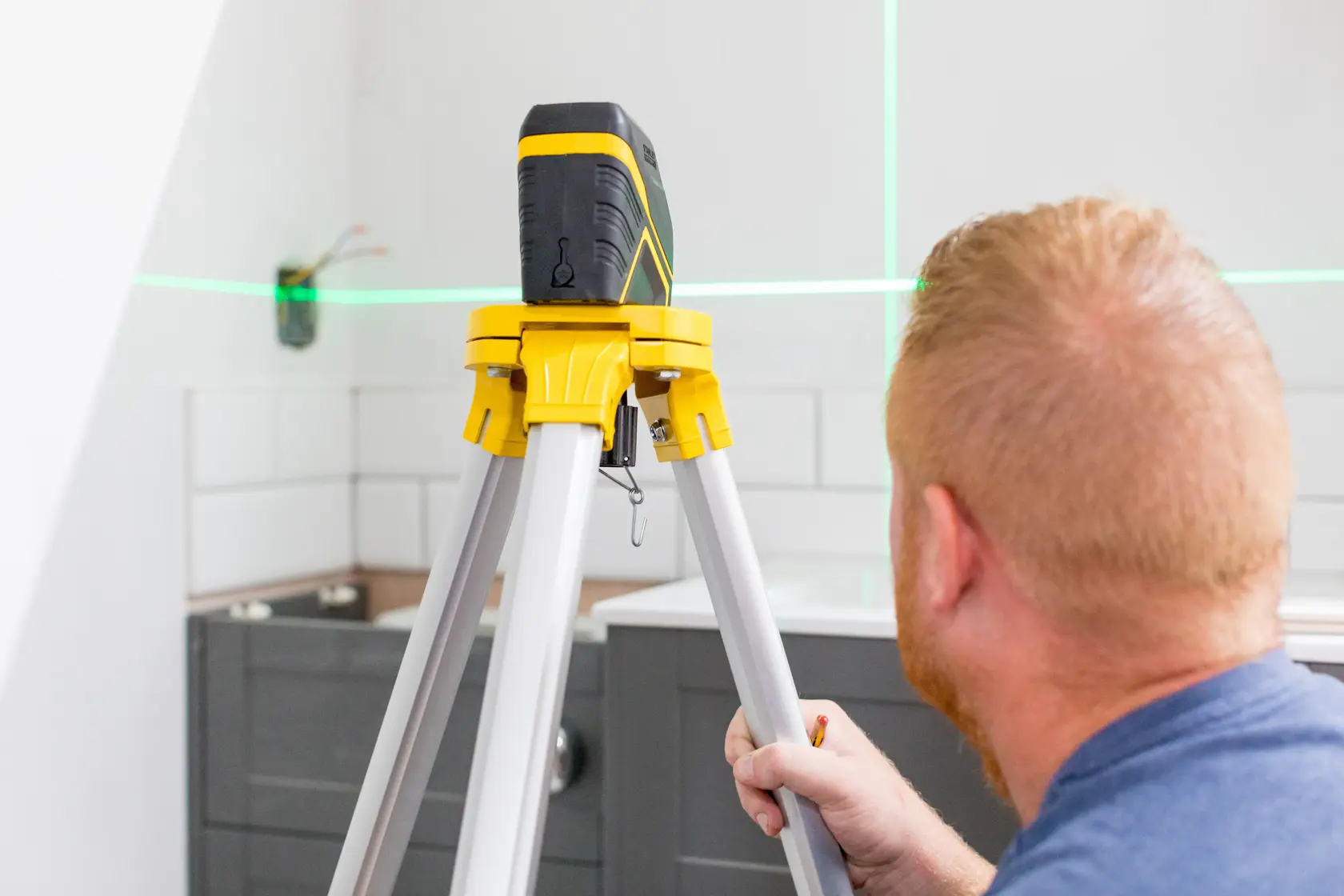 STANLEY FMHT77595-1 laser level on tripod in kitchen, green laser lines projected on wall.