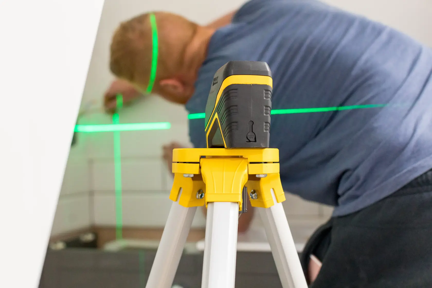 Photo of STANLEY FMHT77595-1 laser level on tripod projecting green lines in interior workspace.