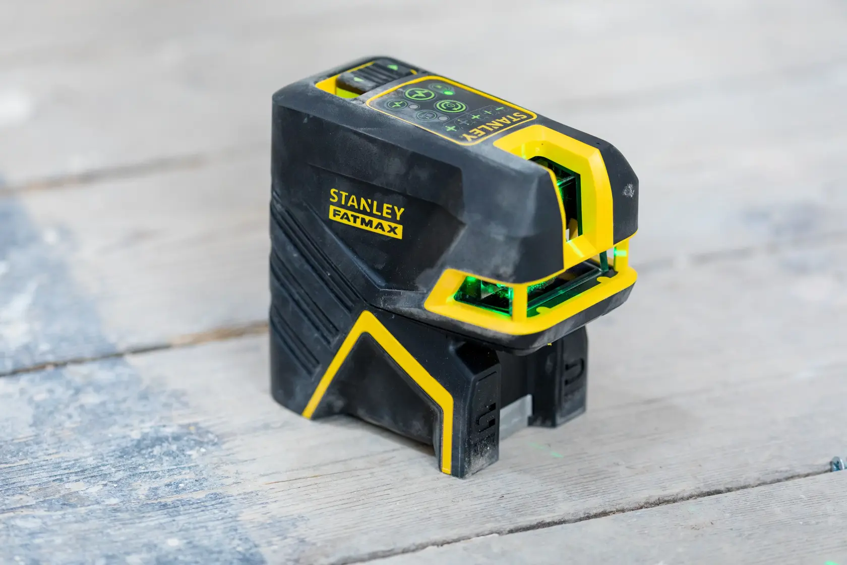 STANLEY FMHT77597-1 laser level, black and yellow, angled view on wood surface.