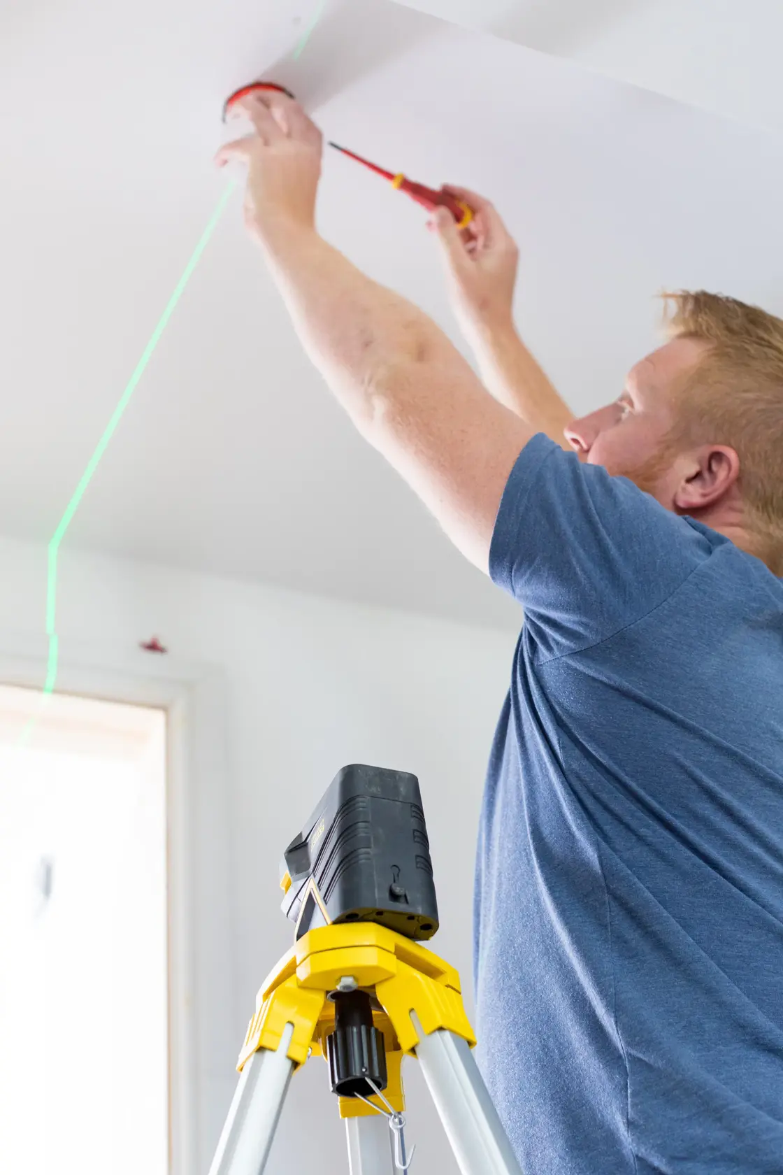 STANLEY FMHT77598-1 laser level on tripod projects green line indoors during ceiling installation.