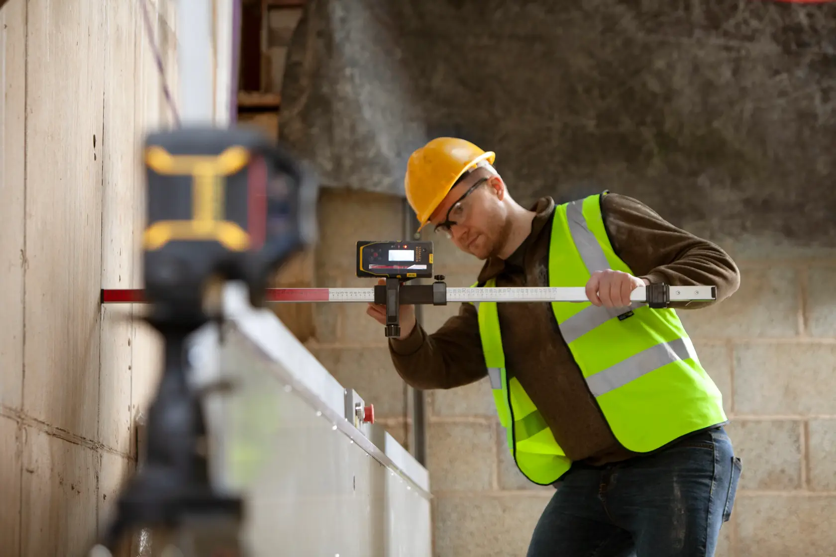STANLEY FMHT77652-0 laser level in use on construction site by worker wearing high-visibility vest.