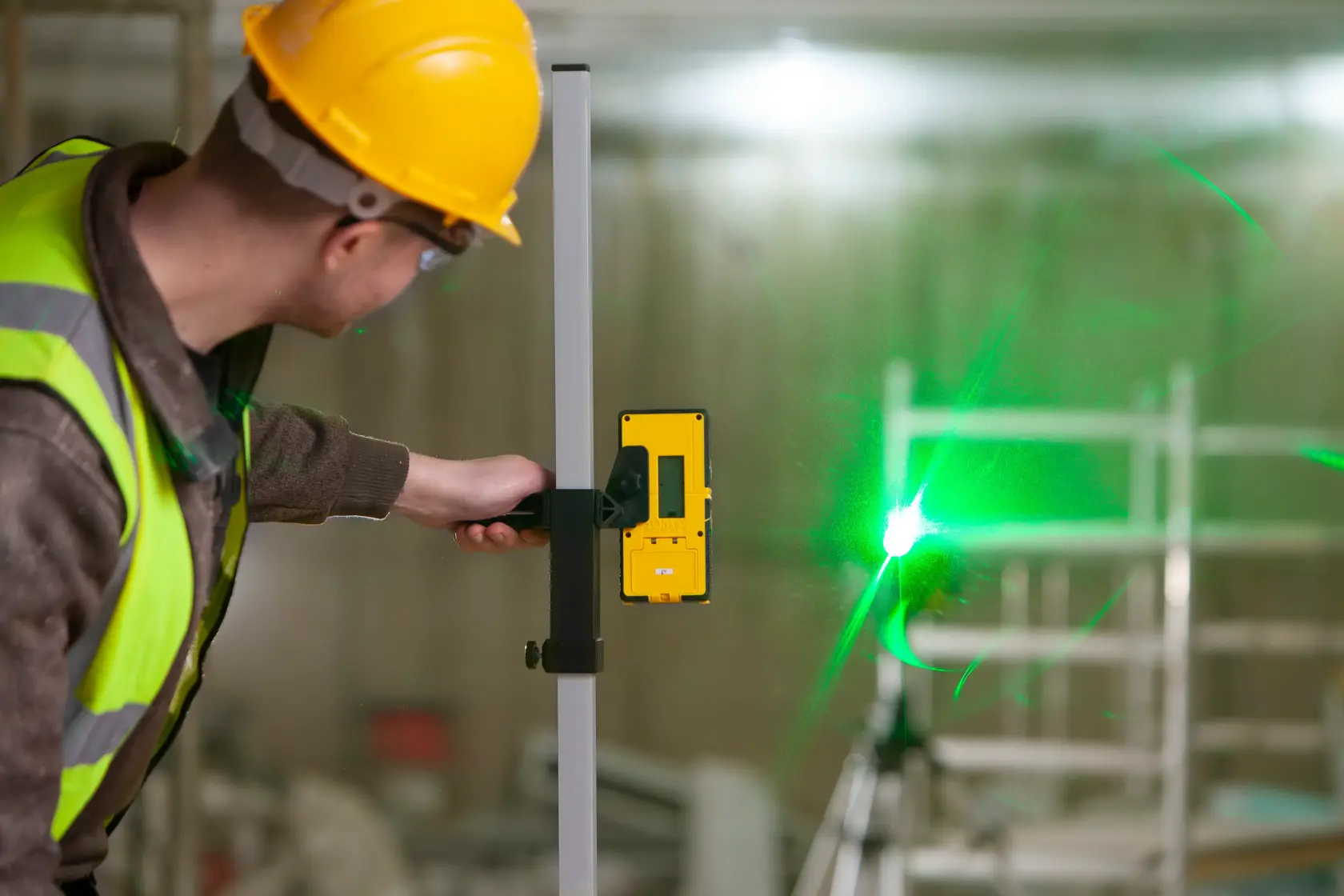 STANLEY FMHT77653-0 laser detector held by worker near green laser beam, construction setting.