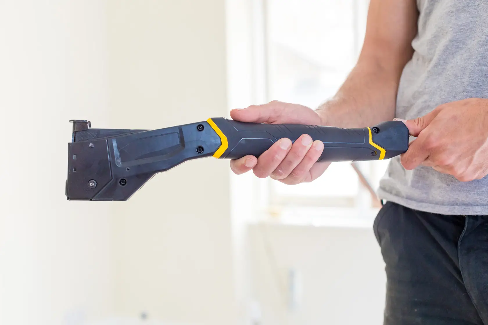 STANLEY FMHT81394-9 heavy-duty stapler gun held in hand, angled view, black and yellow design.
