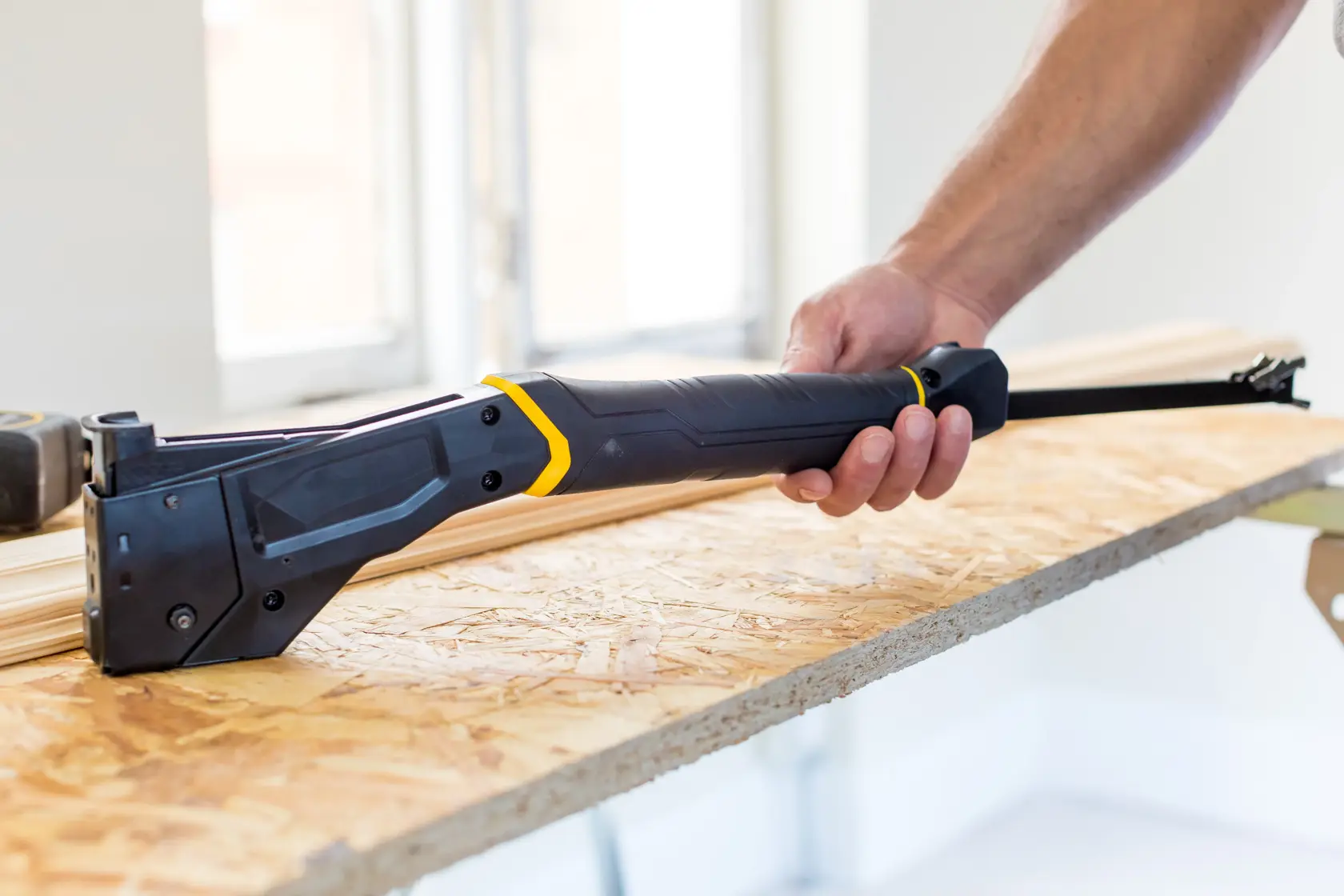 STANLEY FMHT81394-9 hand saw with black and yellow accents, held on a wooden board in a construction setting.