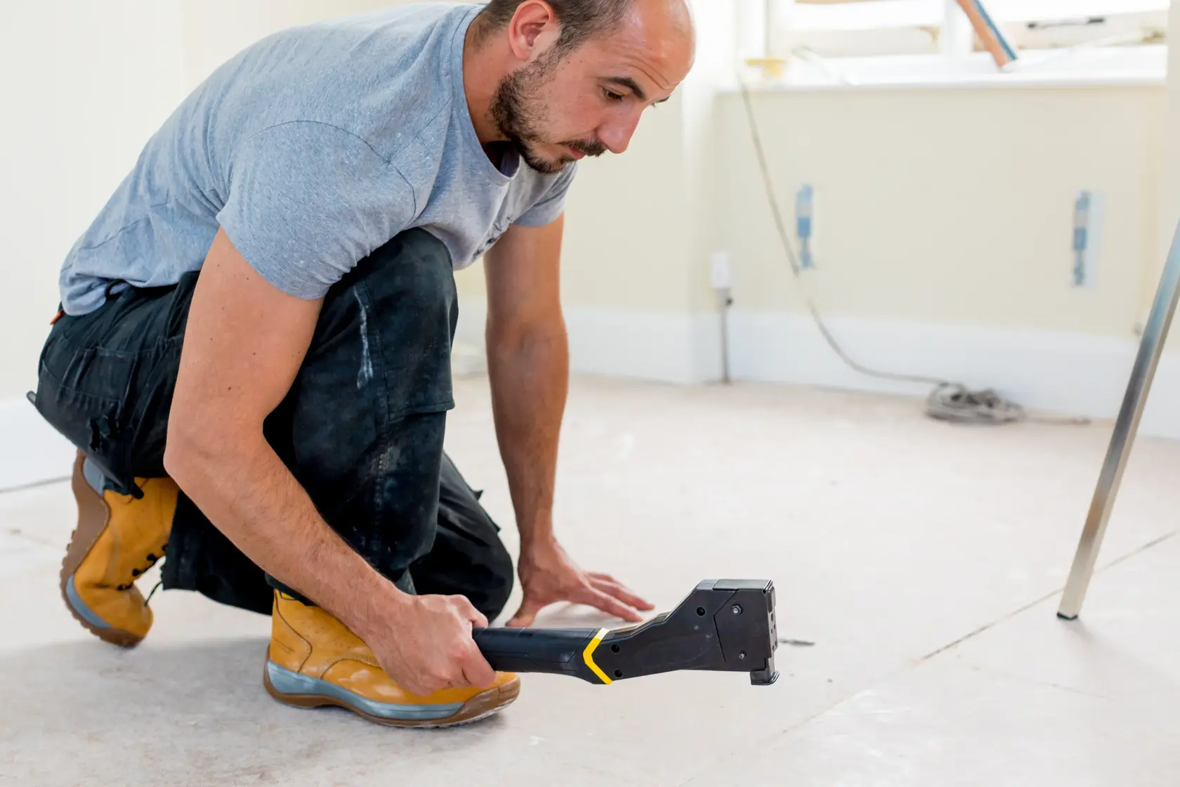 STANLEY FMHT81394-9 staple gun used by worker in construction setting, side angle photography.