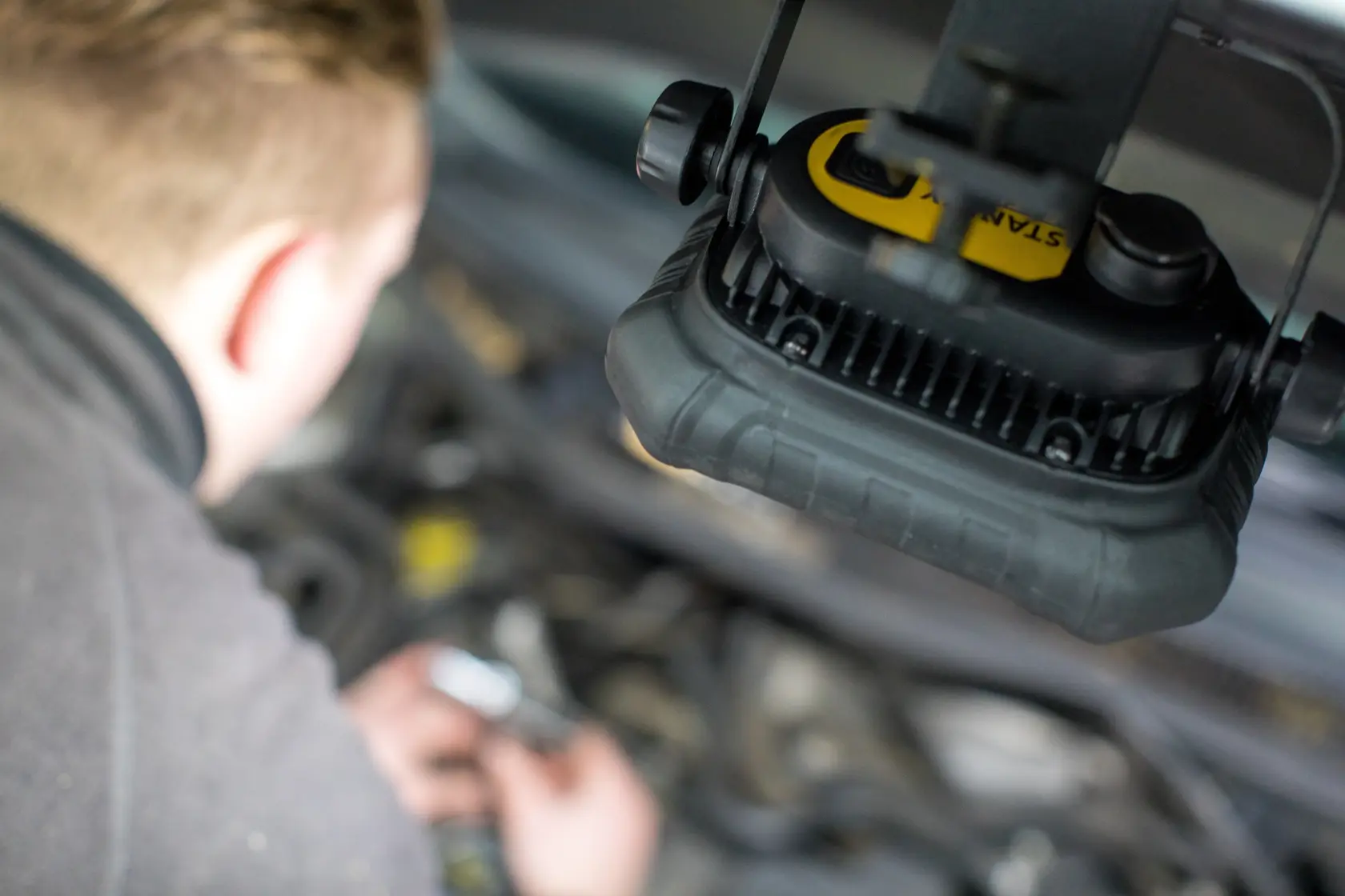 STANLEY FMHT81507-1 work light in use above car engine, close-up photography.
