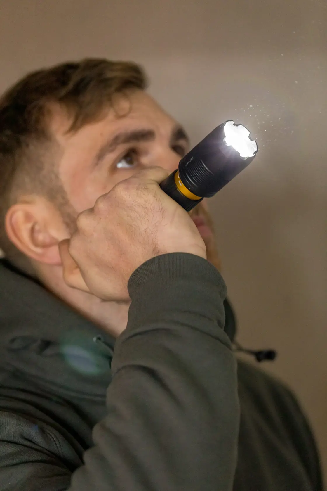Photo of STANLEY FMHT81511-0 flashlight held by person, light beam visible in indoor setting.