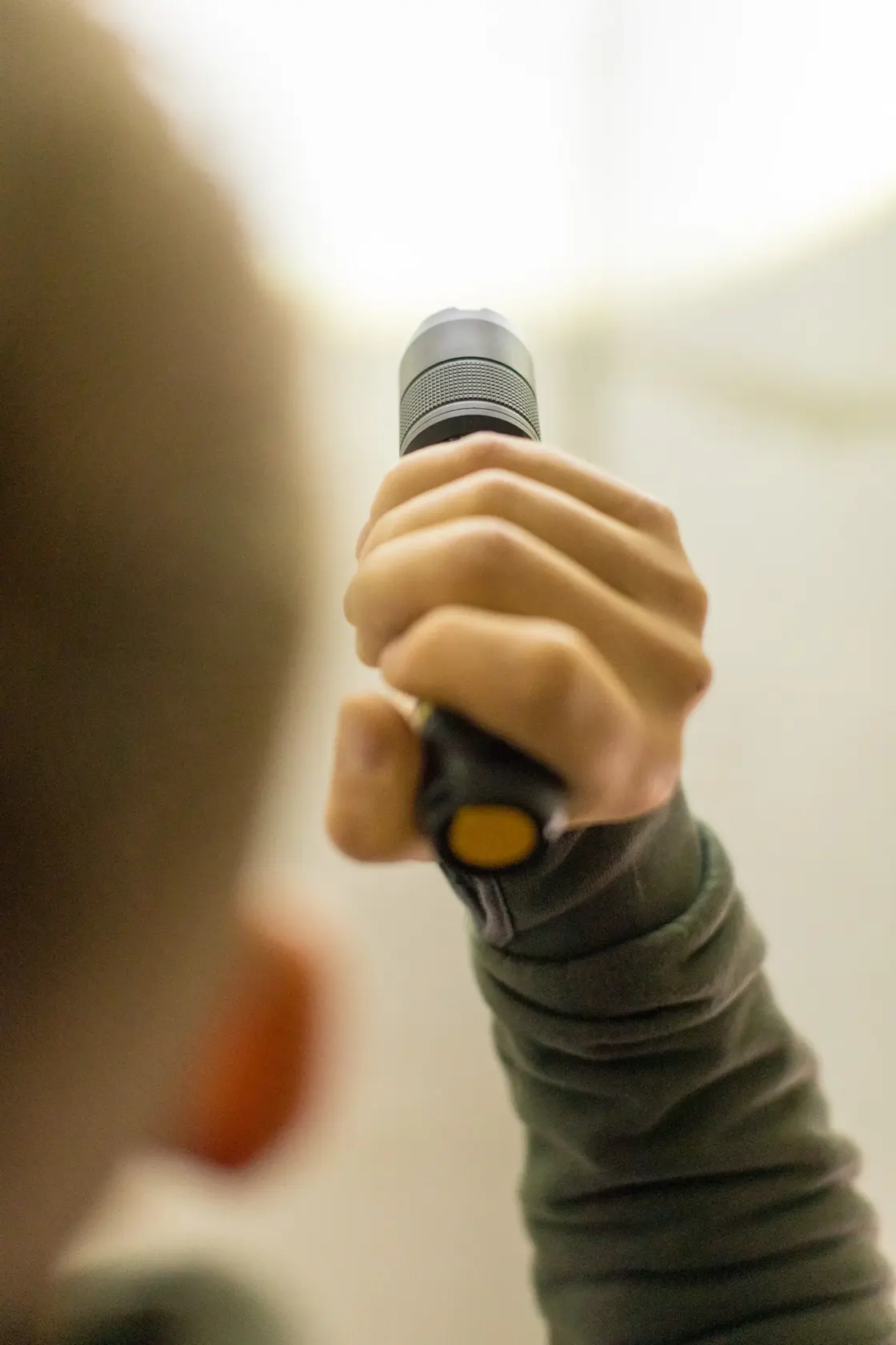 Photo of a person holding a STANLEY FMHT81511-0 flashlight, view focuses on the hand gripping the handle.