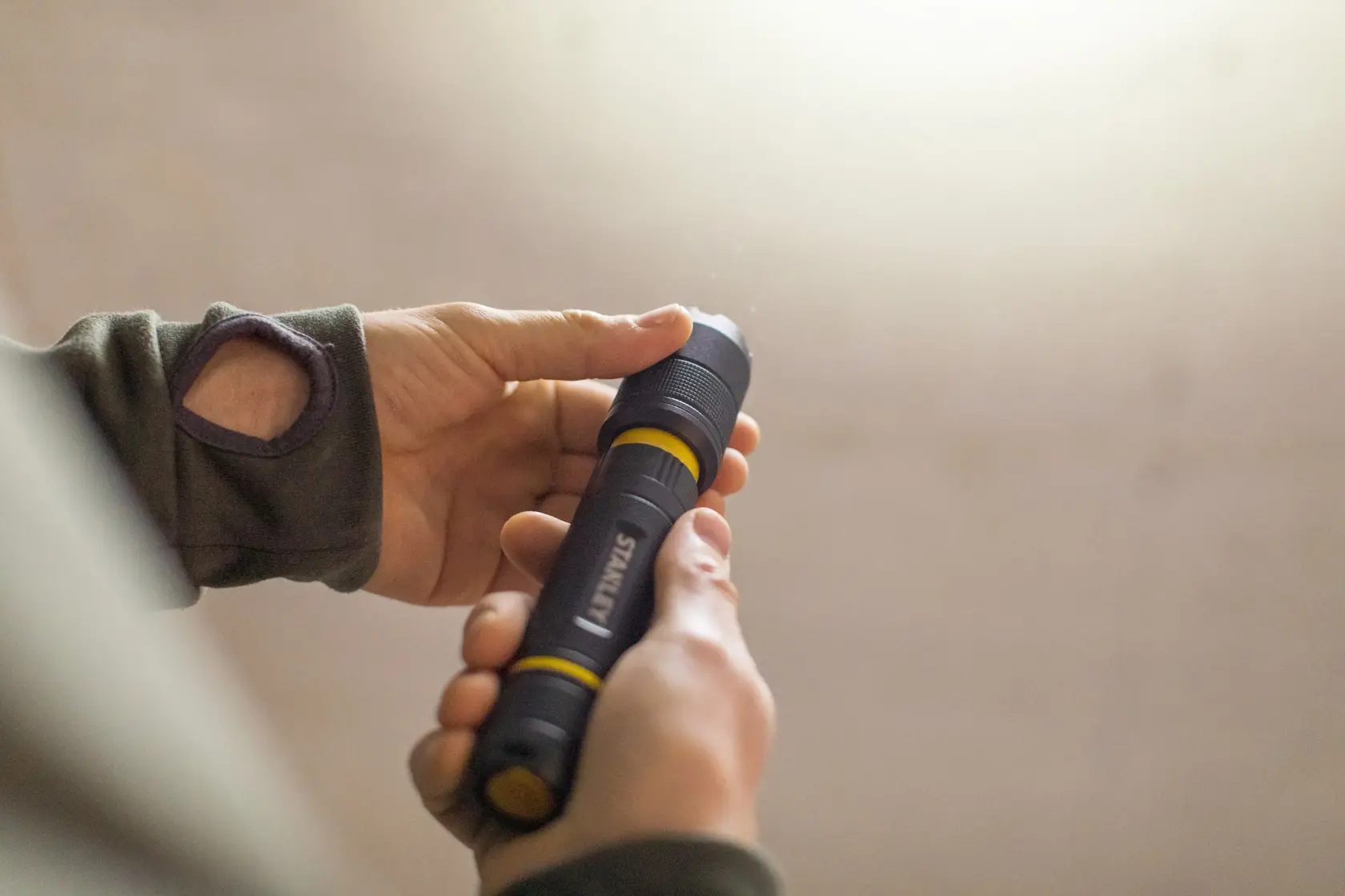 Photo of STANLEY FMHT81511-0 black and yellow flashlight being held in hand.