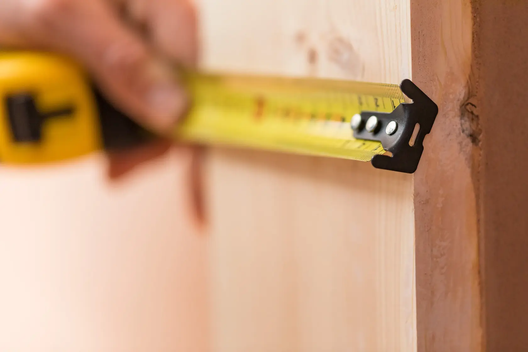 STANLEY FMHT81556-0 tape measure in use measuring wooden plank, close-up side angle.