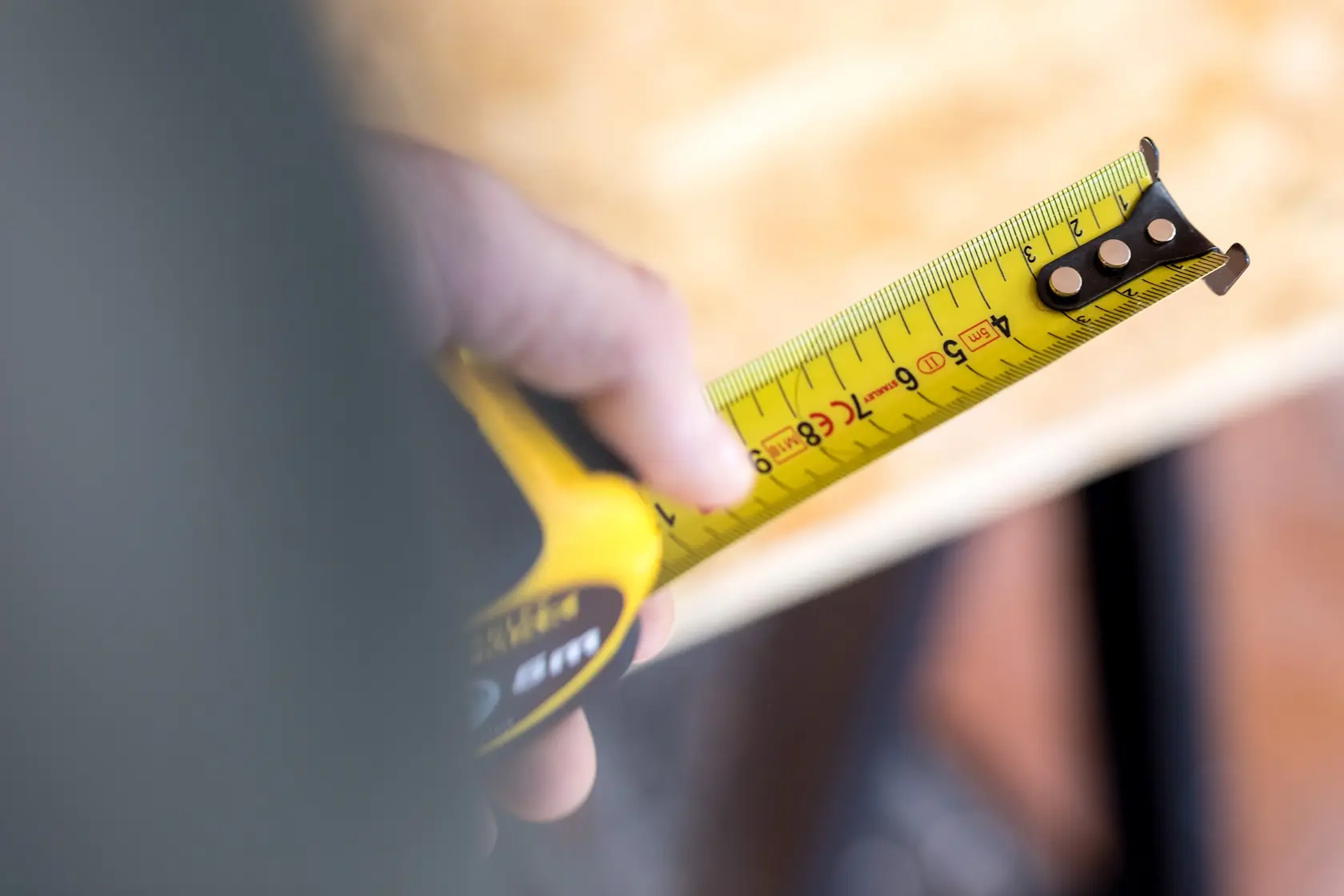 Photo of STANLEY FMHT81556-0 yellow tape measure extended over wood surface, close-up view.