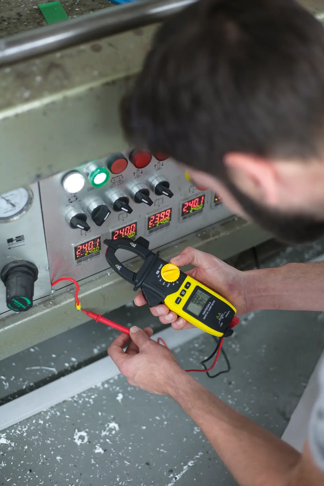 Photo of STANLEY FMHT82564-0 digital clamp meter being used to test voltage on industrial control panel.