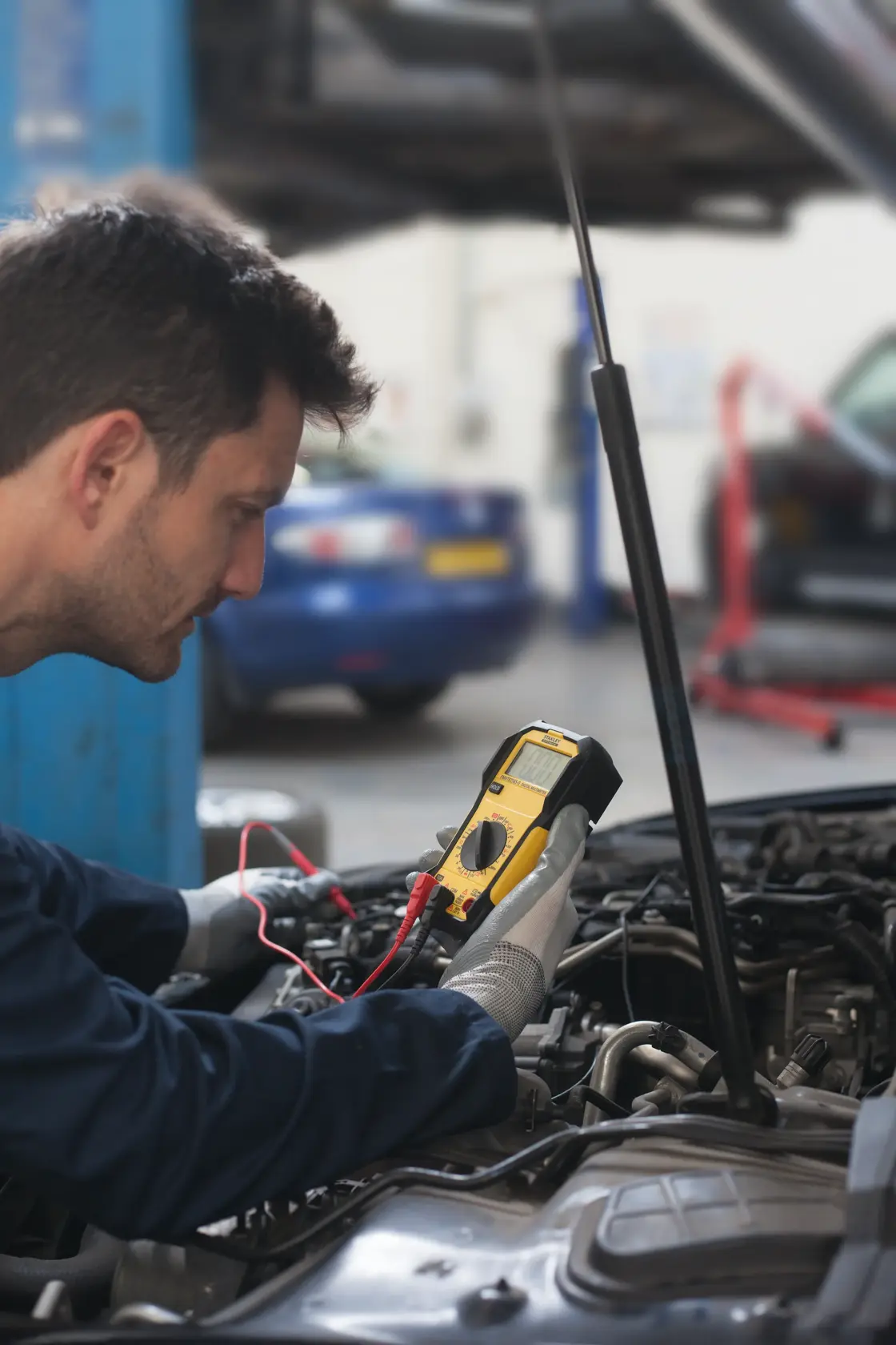 Photo of STANLEY FMHT82565-0 digital multimeter in use by mechanic testing car engine.