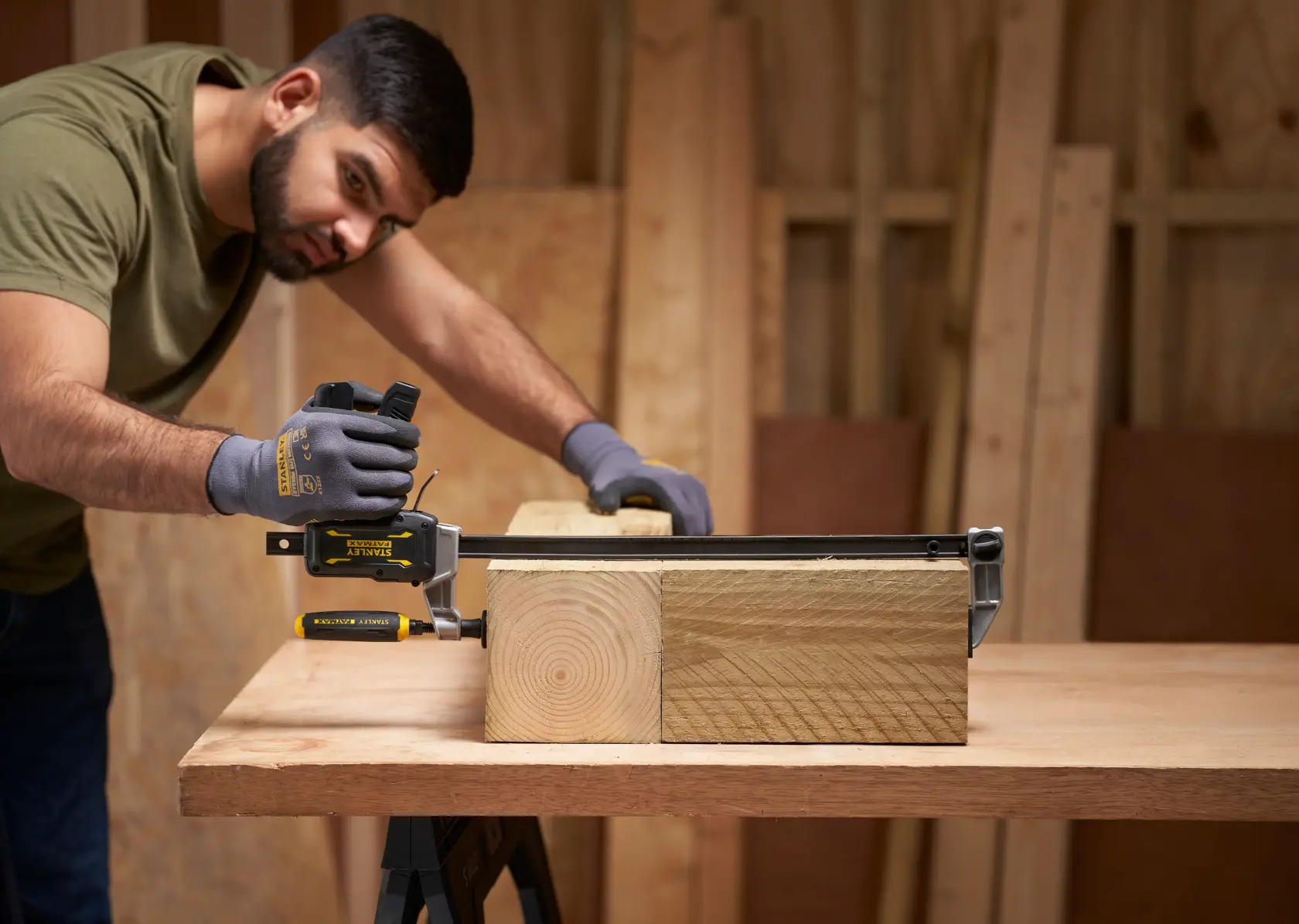 STANLEY FMHT83007-0 bar clamp being used to secure wooden beams on a workbench in a workshop setting.