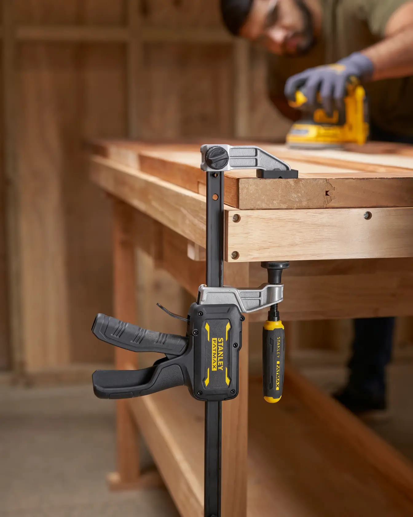 STANLEY FMHT83008-0 heavy-duty bar clamp attached to wooden workbench, side angle photo.