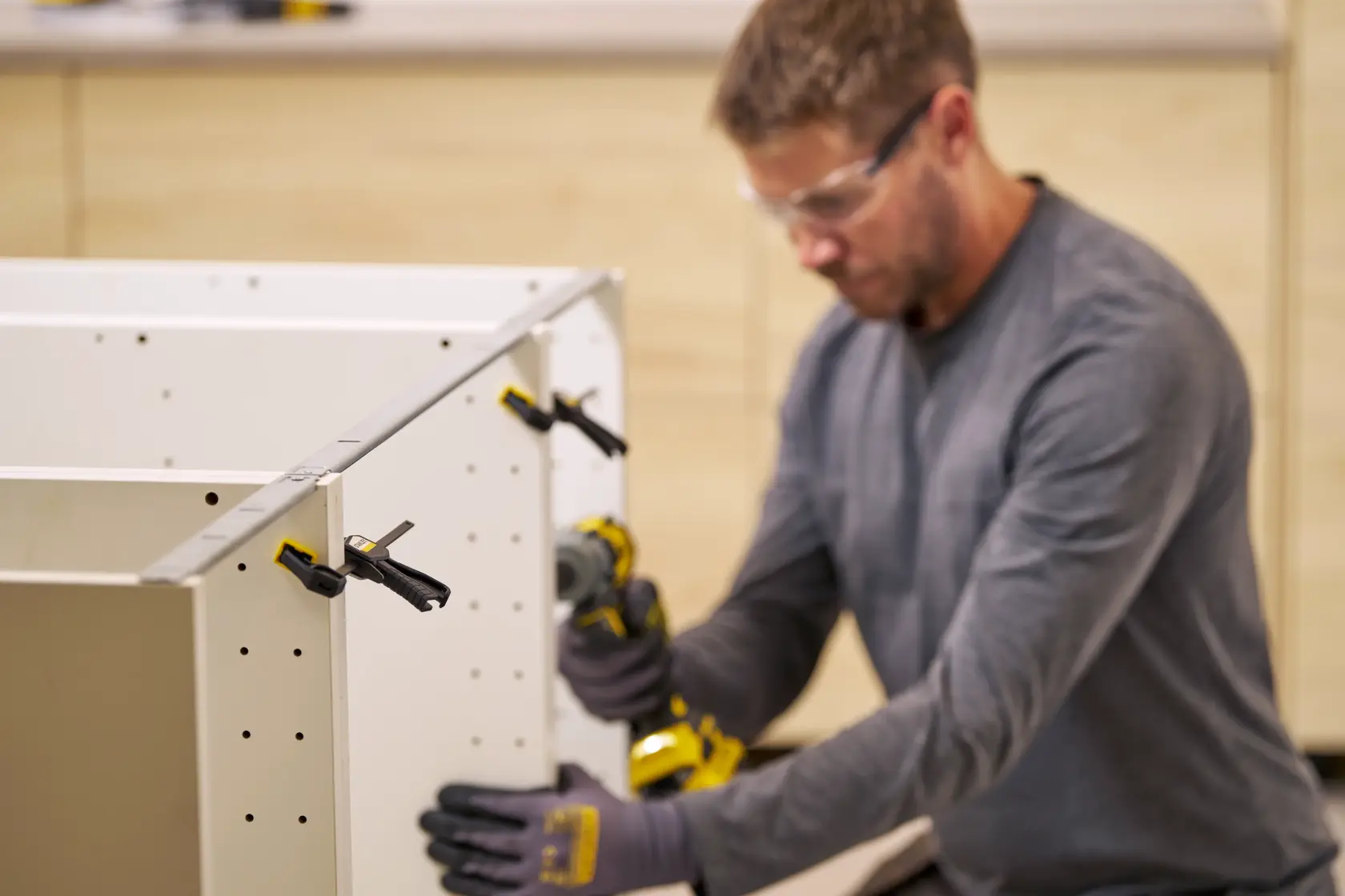 STANLEY FMHT83270-0 bar clamps securing white cabinet panels during assembly, close-up, workshop setting.
