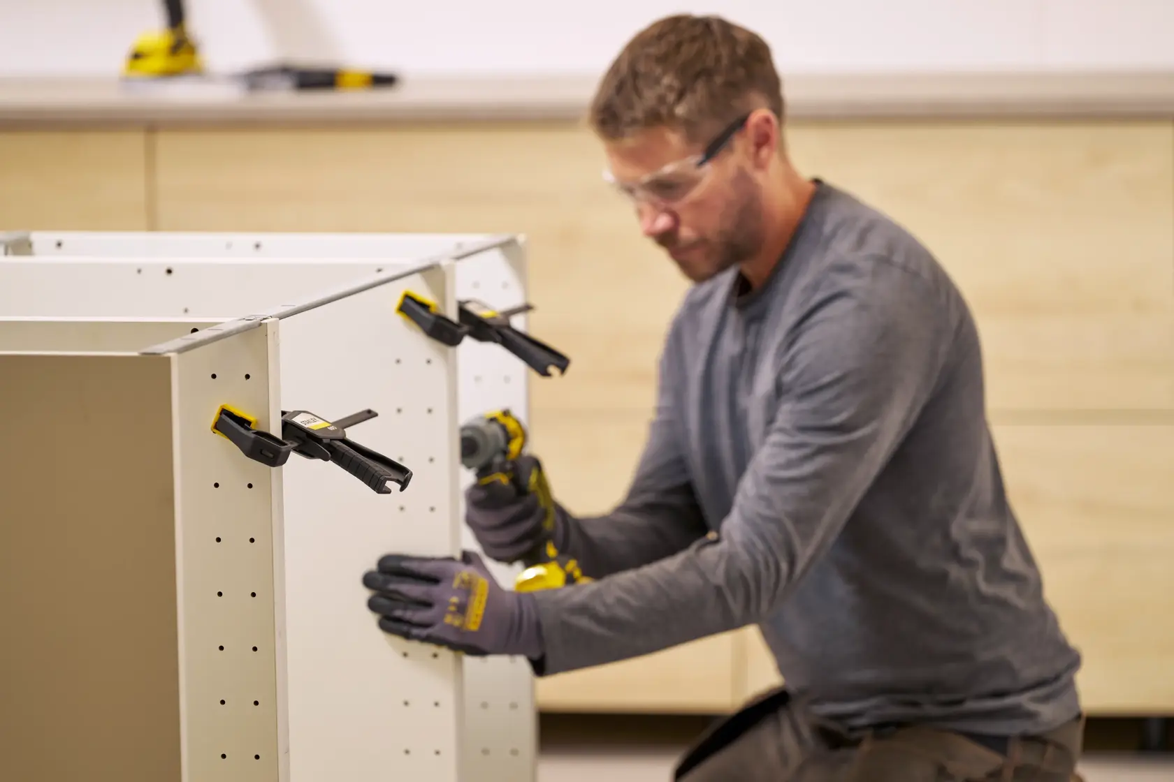 STANLEY FMHT83271-0 quick-adjust clamps used to hold white cabinet panels during assembly, workshop setting.