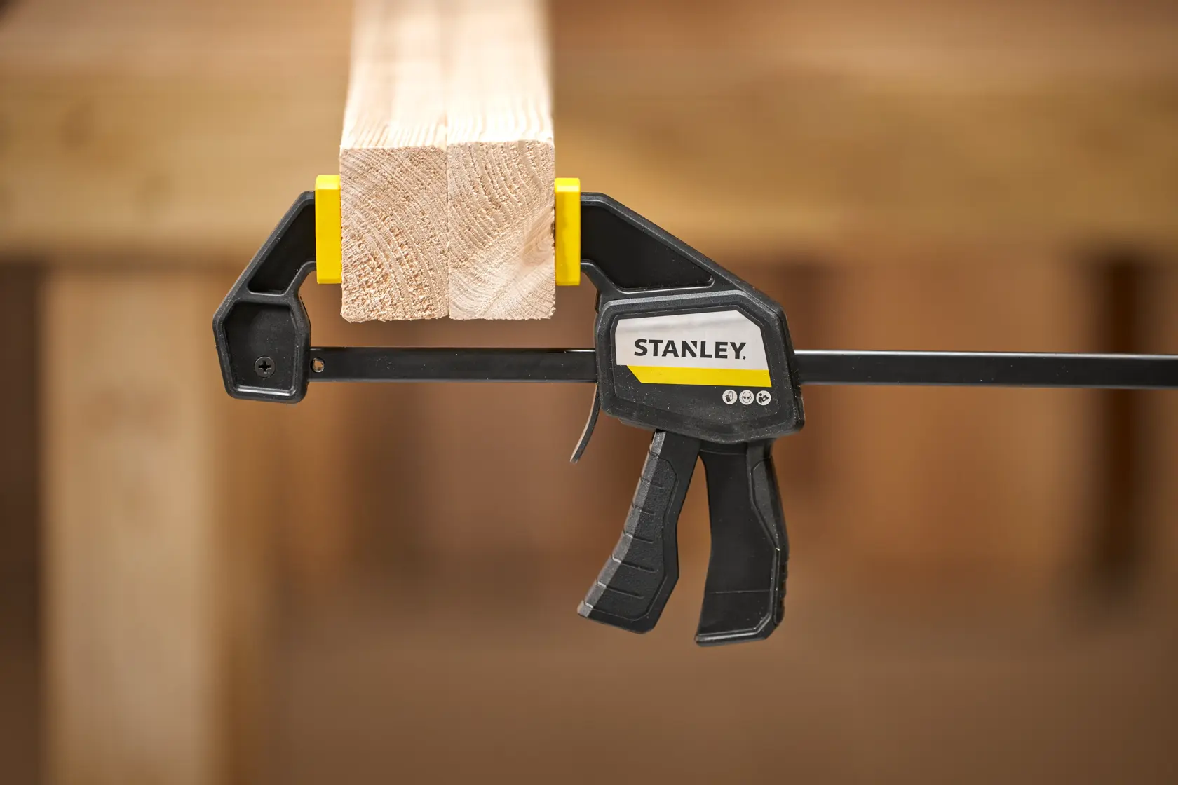 STANLEY FMHT83271-0 trigger clamp holding wooden beam, product side view, woodworking context.