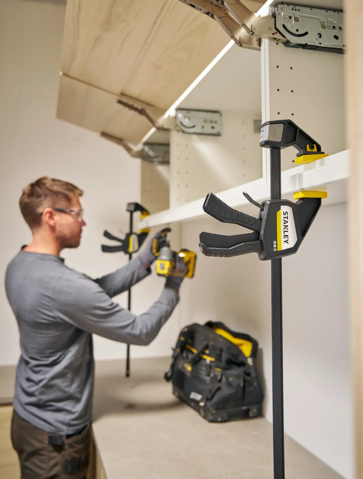 Photo of STANLEY FMHT83276-0 bar clamp holding shelf during cabinet installation.