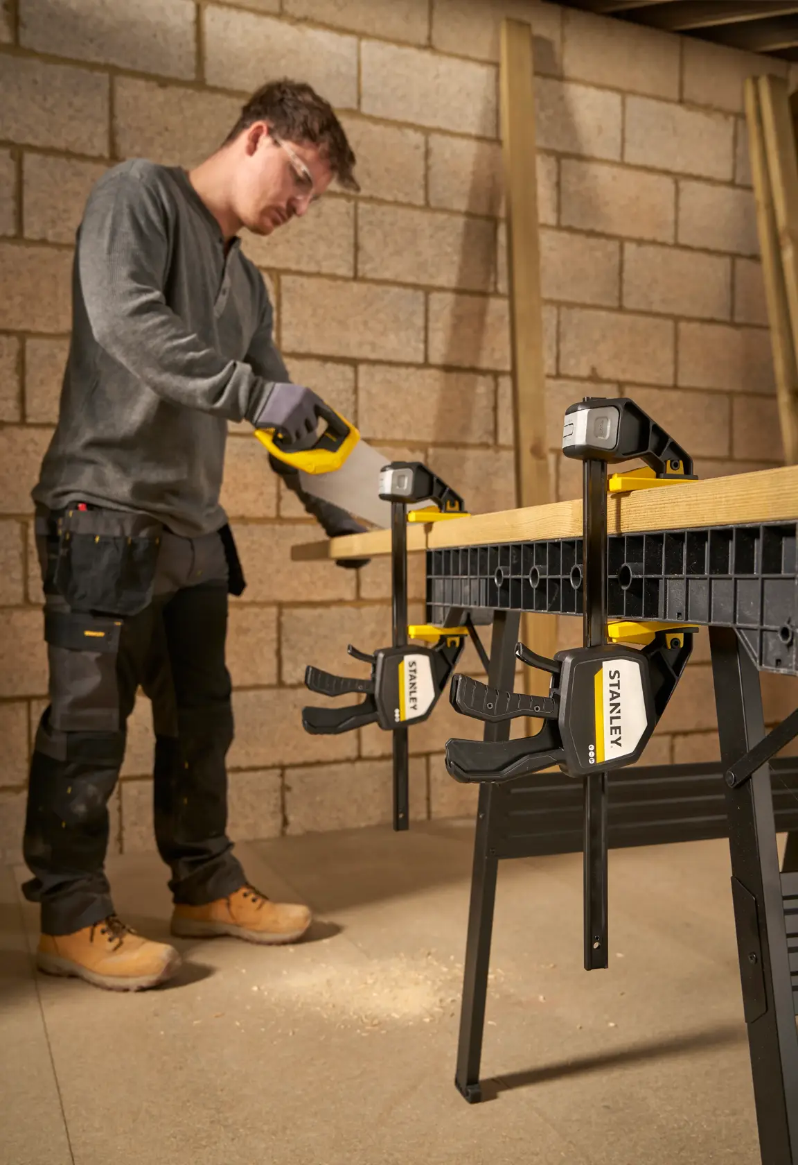 Photo of STANLEY FMHT83279-0 bar clamps securing wood to a workbench in a workshop setting.