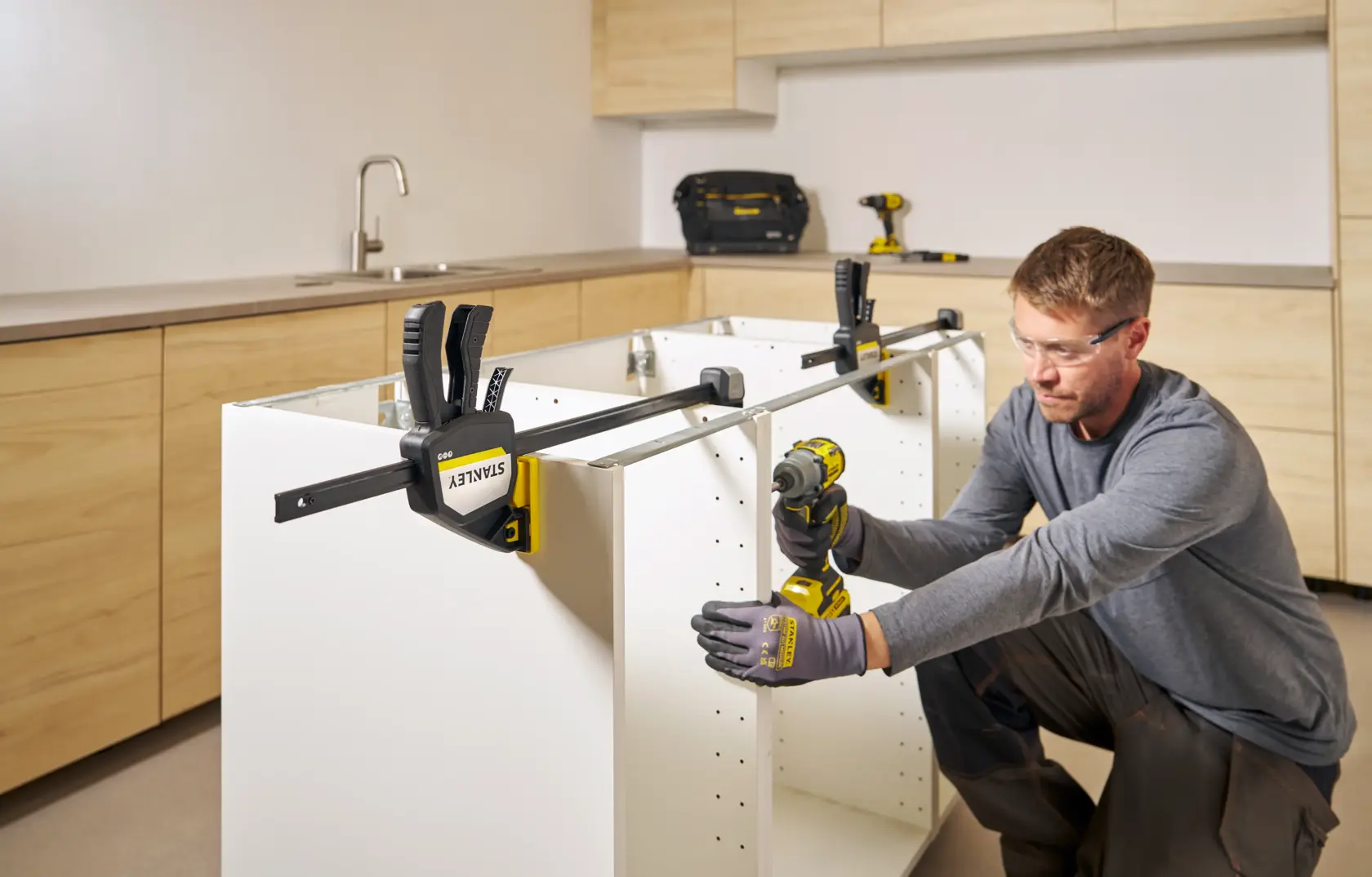 STANLEY FMHT83280-0 bar clamp used on white cabinet during assembly in kitchen setting.