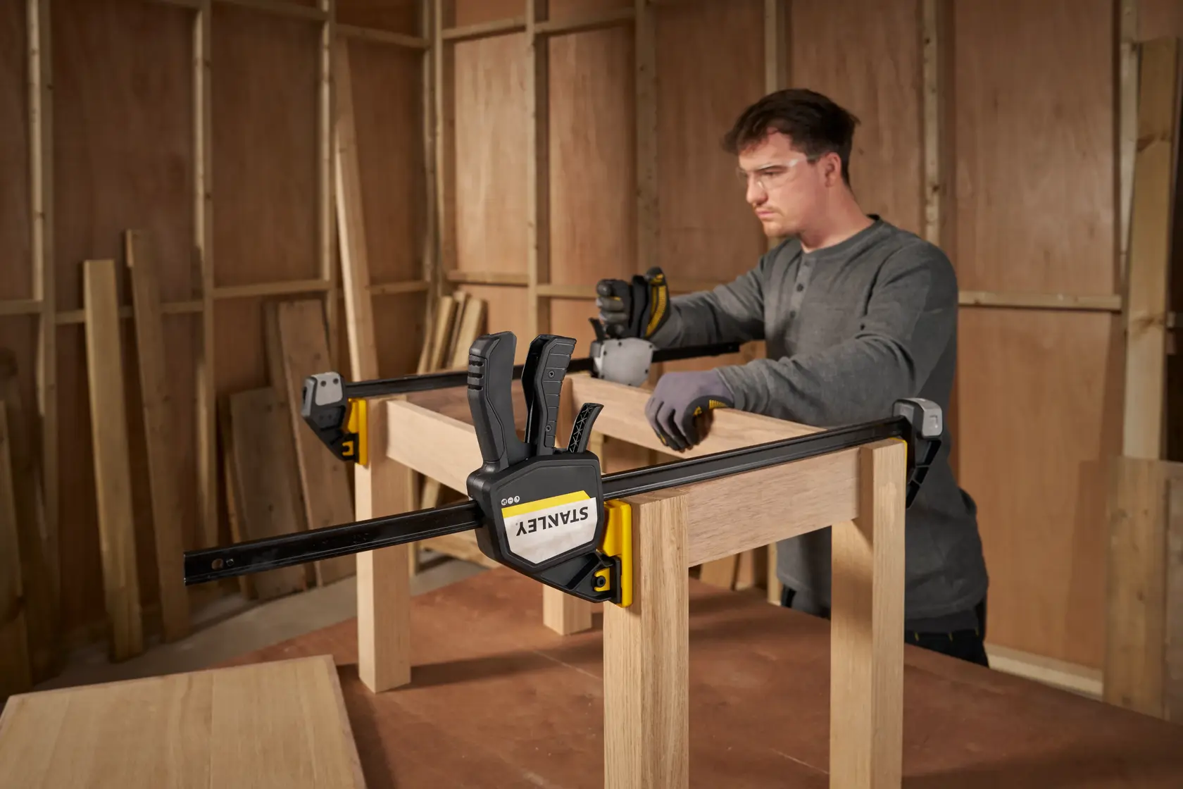 Photo of STANLEY FMHT83281-0 bar clamp securing wooden frame during assembly in workshop setting.