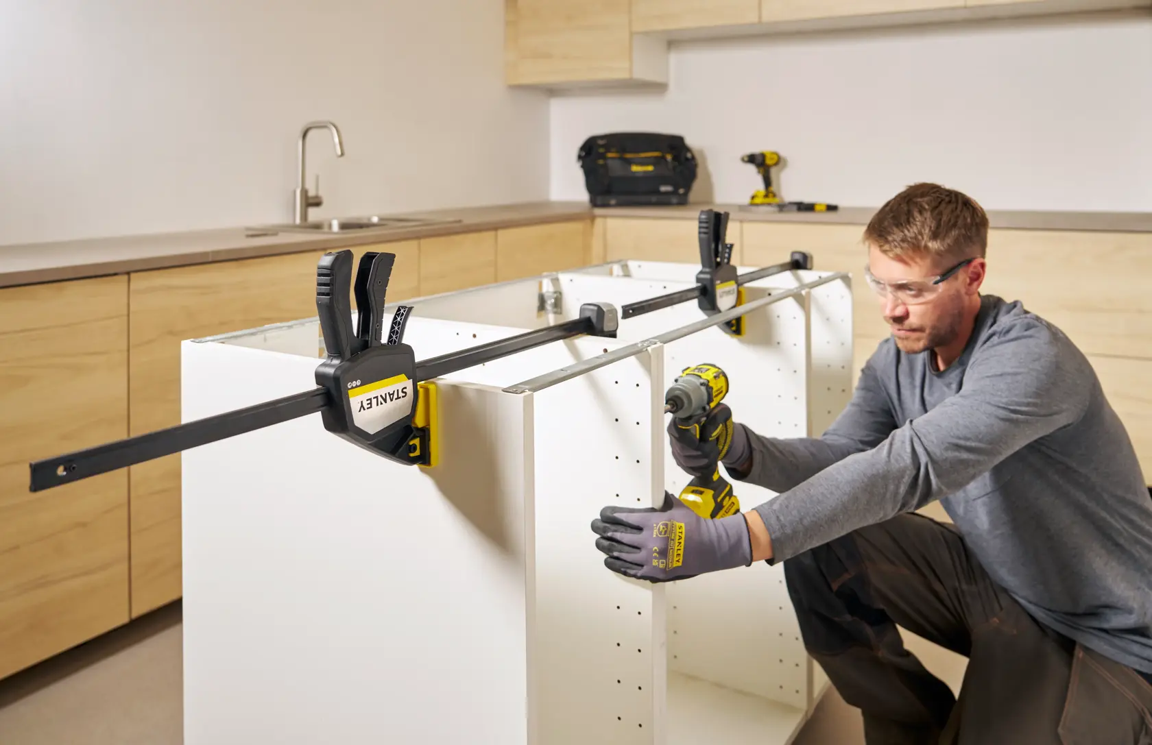 Photo of STANLEY FMHT83281-0 bar clamp securing white cabinet in kitchen assembly scene.