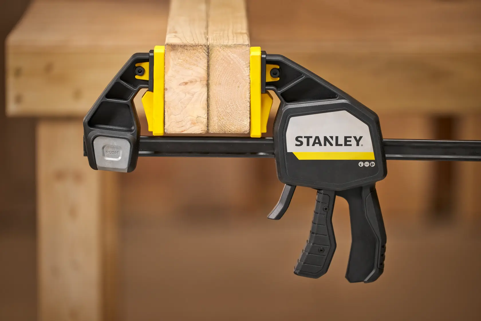 STANLEY FMHT83281-0 trigger clamp securing two wooden boards on a workbench, close-up side view.