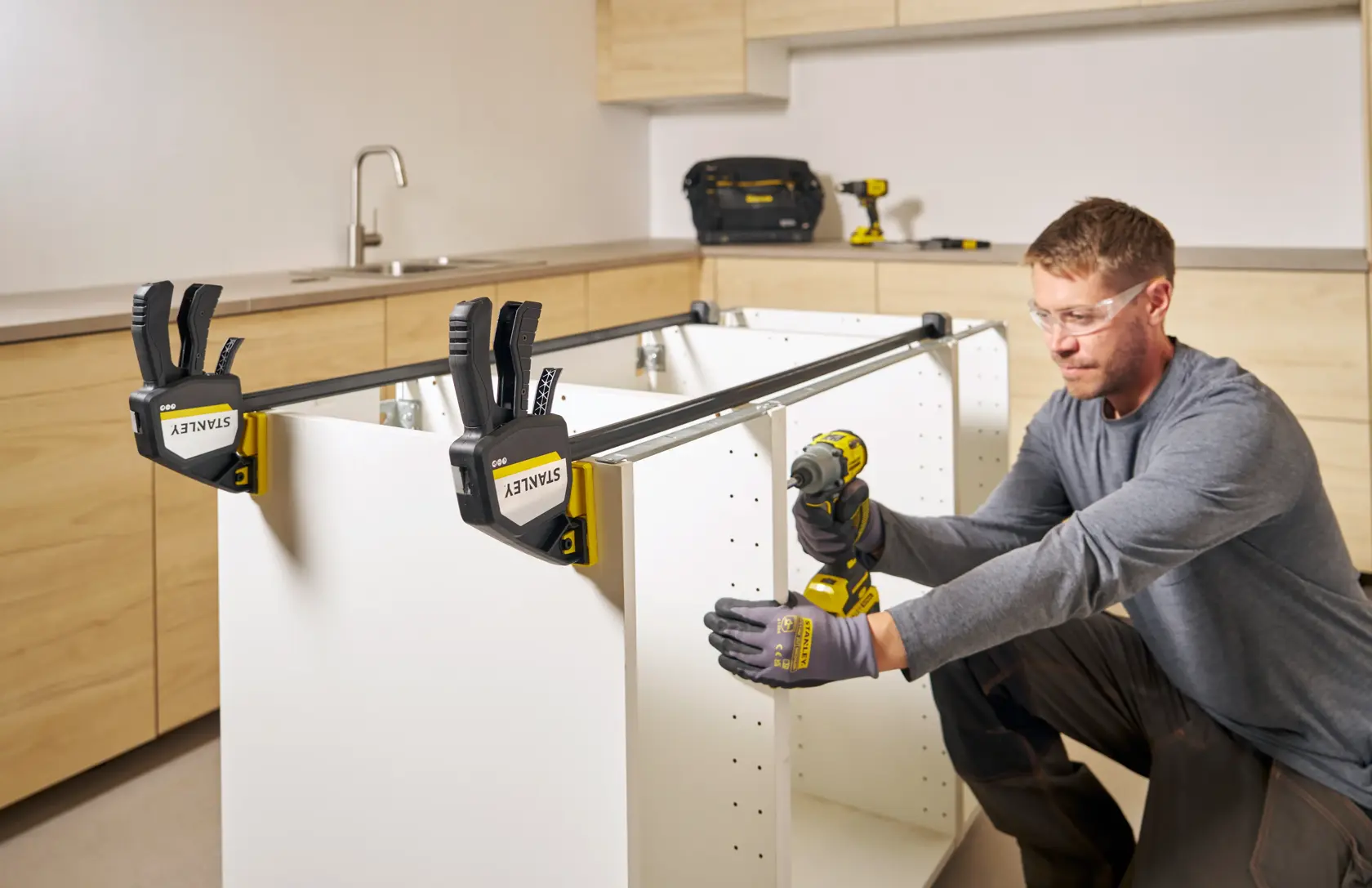 Photo of STANLEY FMHT83282-0 clamps securing white cabinet panels during assembly in a kitchen setting.