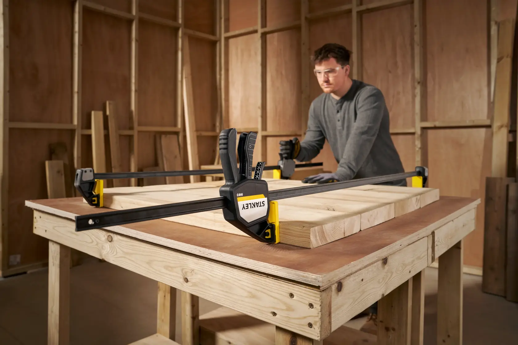 STANLEY FMHT83283-0 large bar clamp securing wooden boards on workbench in woodworking shop.