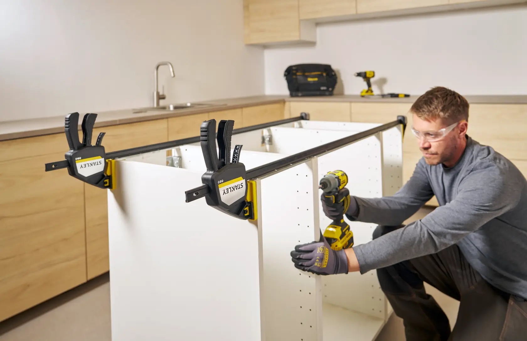 Photo of STANLEY FMHT83283-0 bar clamps securing a cabinet frame during assembly in a kitchen.