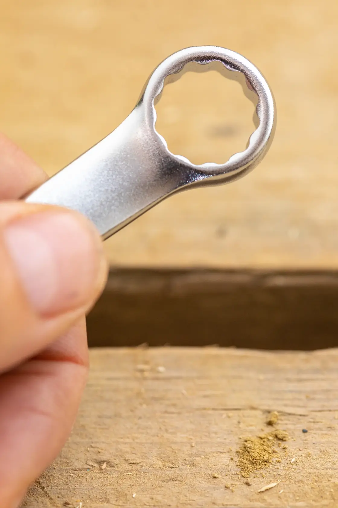 STANLEY FMMT13032-0 box end wrench, close-up view held by hand, silver finish, on wooden surface.